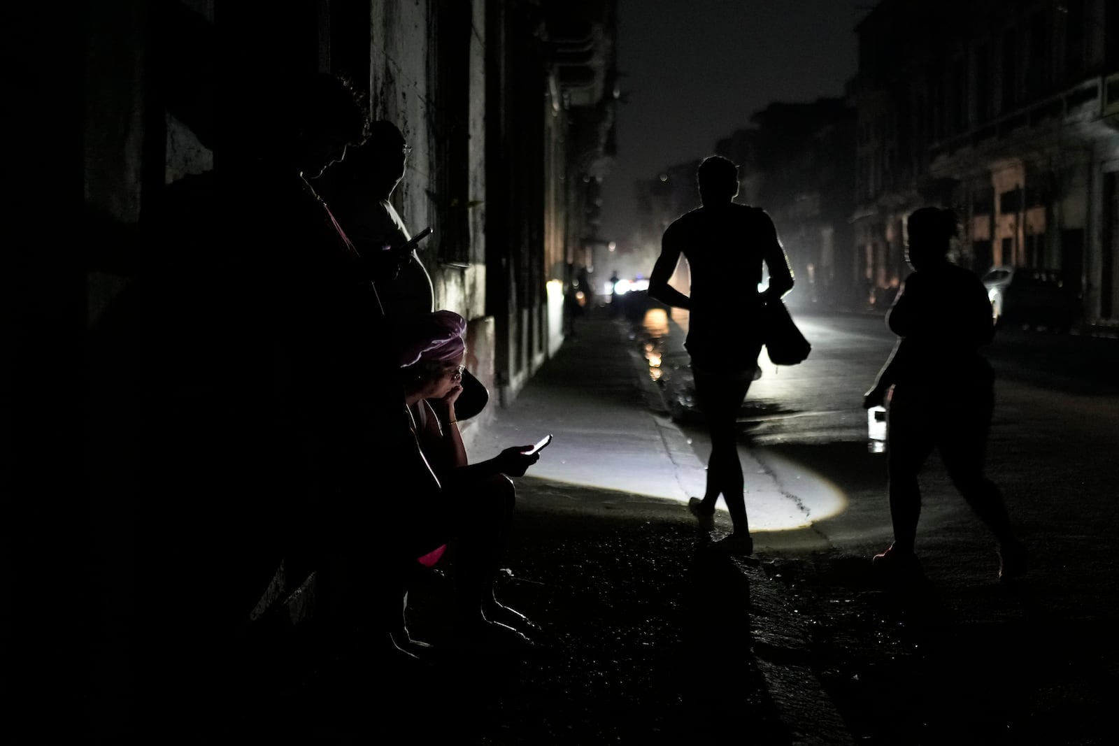 Residents walk on a street during a general blackout in Havana, Cuba, Friday, March 14, 2025. (AP Photo/Ramon Espinosa)