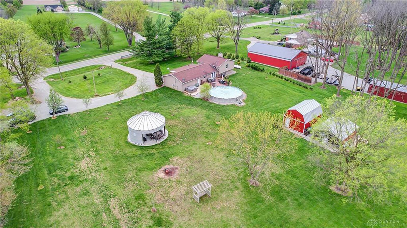 The house sits on nearly 5 acres; and the backyard has a wood deck with railings, above-ground pool, steel gazebo with electricity, a wood swing with pergola, a barn and covered parking. The driveway is circular with additional parking. 