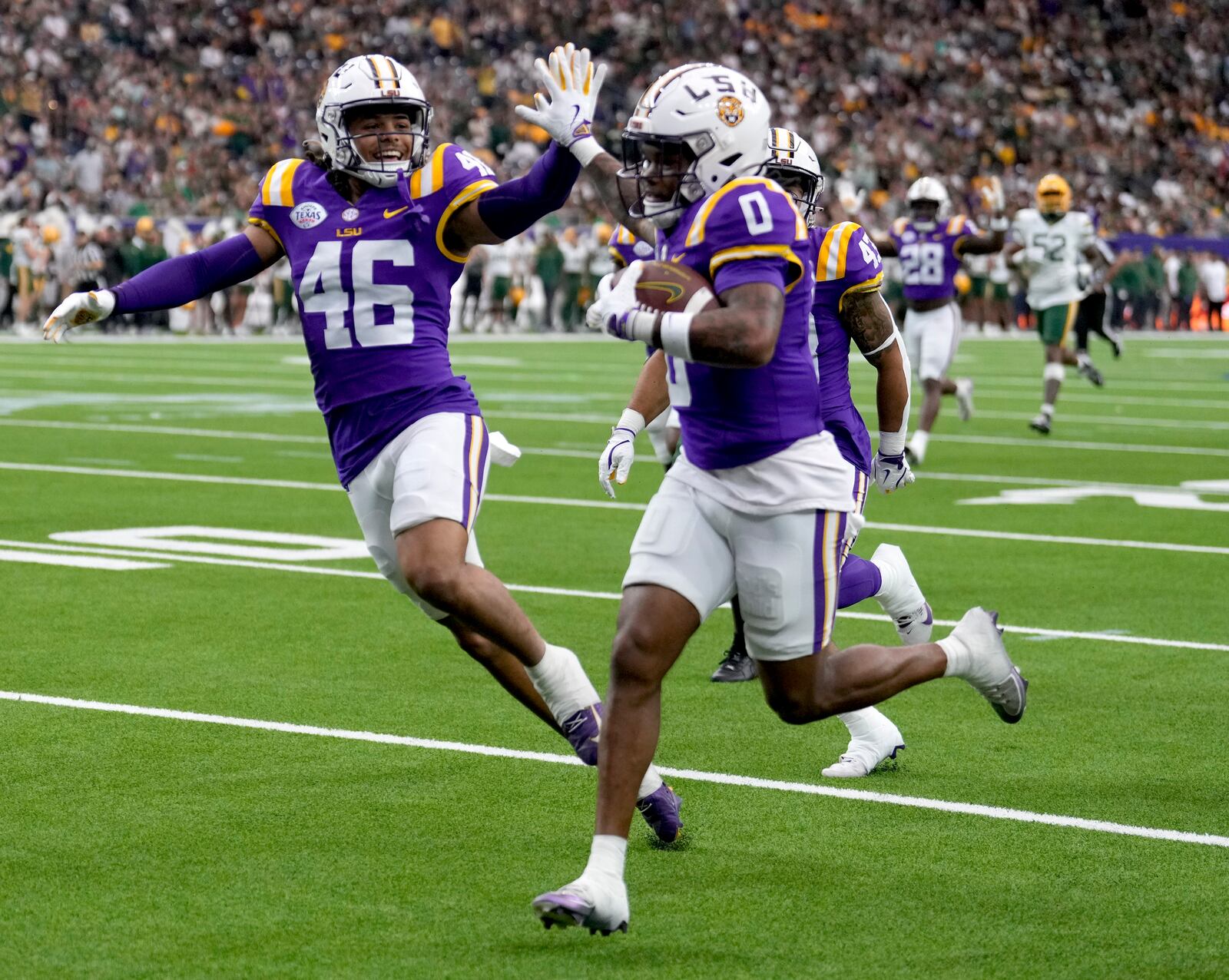 LSU linebacker Tylen Singleton, left, gives wide receiver Zavion Thomas (0) a high-five as Thomas returns a kickoff for a touchdown during the first half of the Texas Bowl NCAA college football game Tuesday, Dec. 31, 2024, in Houston. (Brett Coomer/Houston Chronicle via AP)