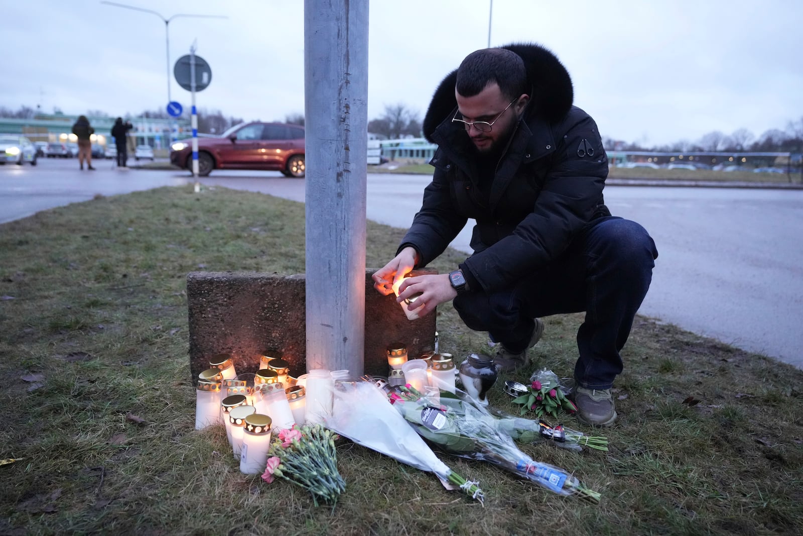 A man lights a candle at a makeshift memorial near the scene of a shooting at an adult education center on the outskirts of Orebro, Sweden, Wednesday, Feb. 5, 2025. (AP Photo/Sergei Grits)