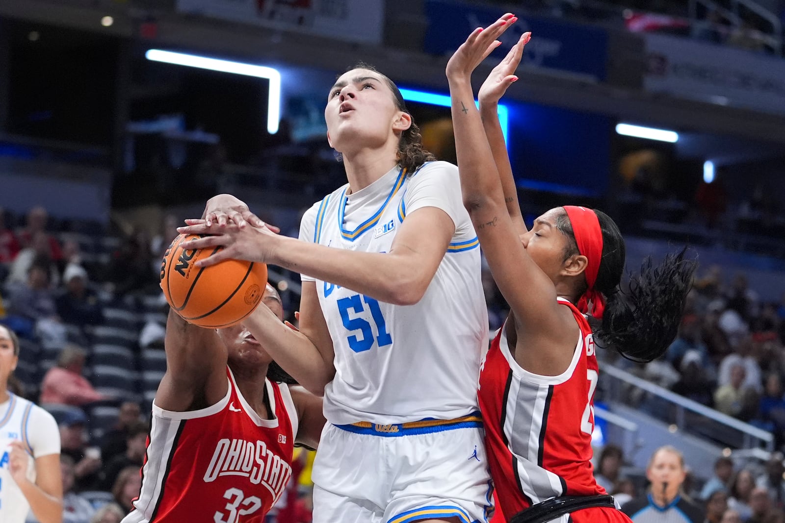 UCLA center Lauren Betts (51) drives on Ohio State forward Cotie McMahon (32) and Chance Gray (21) during the first half of an NCAA college basketball game in the semifinals of the Big Ten Conference tournament in Indianapolis, Saturday, March 8, 2025. (AP Photo/Michael Conroy)