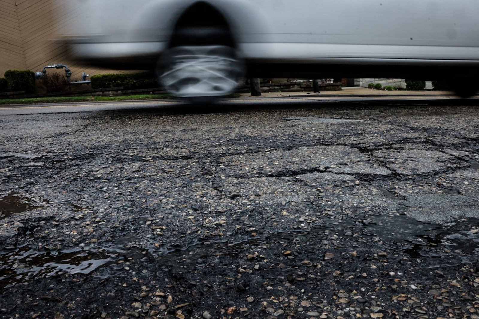 A vehicle negotiates cracked, bumpy pavement on Wayne Ave. between Tanks Bar and Wyoming St. Friday March 31, 2023. JIM NOELKER/STAFF