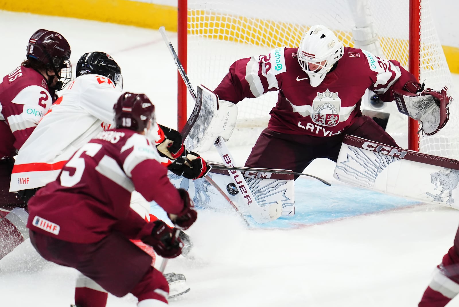 Latvia goaltender Linards Feldbergs (29) makes a save on Canada's Cole Beaudoin, second left, as Latvia's Krisjanis Sarts (2) defends during the third period of a IIHF World Junior Hockey Championship preliminary round game in Ottawa, Ontario on Friday, Dec. 27, 2024. (Sean Kilpatrick/The Canadian Press via AP)