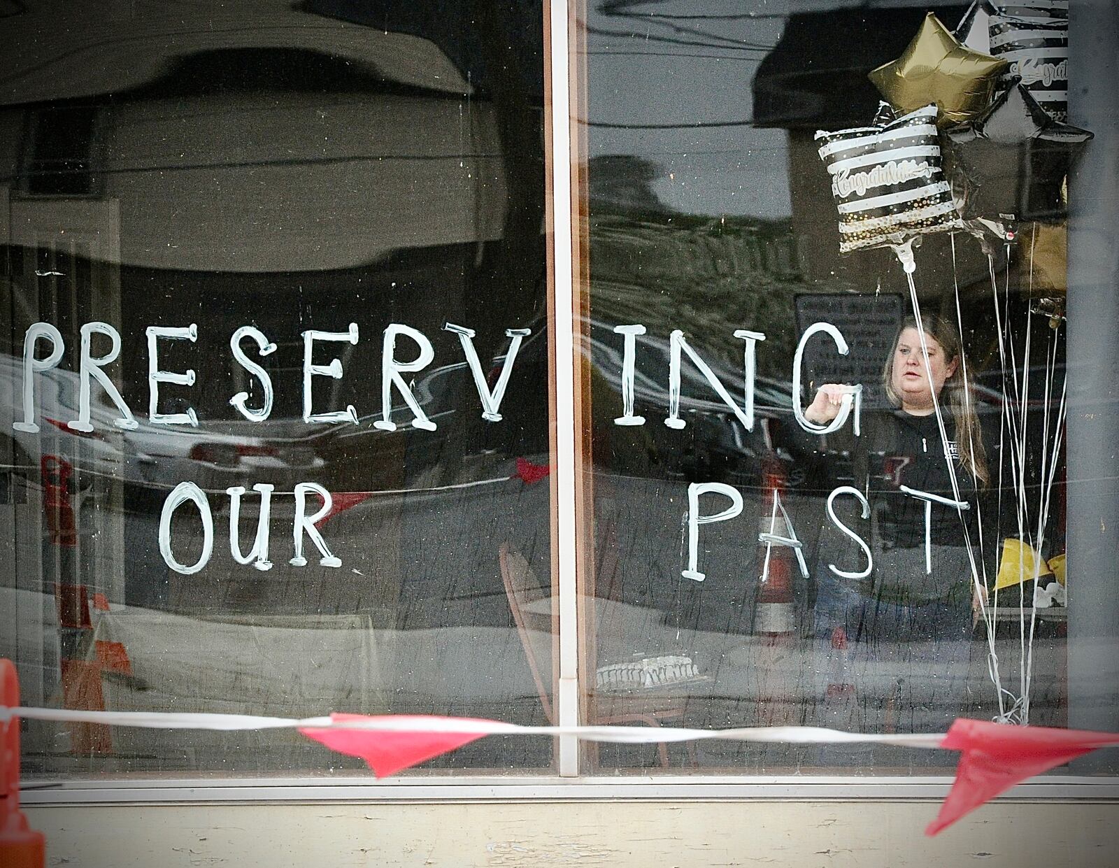 Julie Carter, a member of the Troy Historic Preservations Alliance, writes on the windows of the Tavern / IOOF / Old Courthouse building Friday April 19, 2024. West Main Street in front of the building was reopened to traffic Friday after a near 10-month closure. MARSHALL GORBY\STAFF