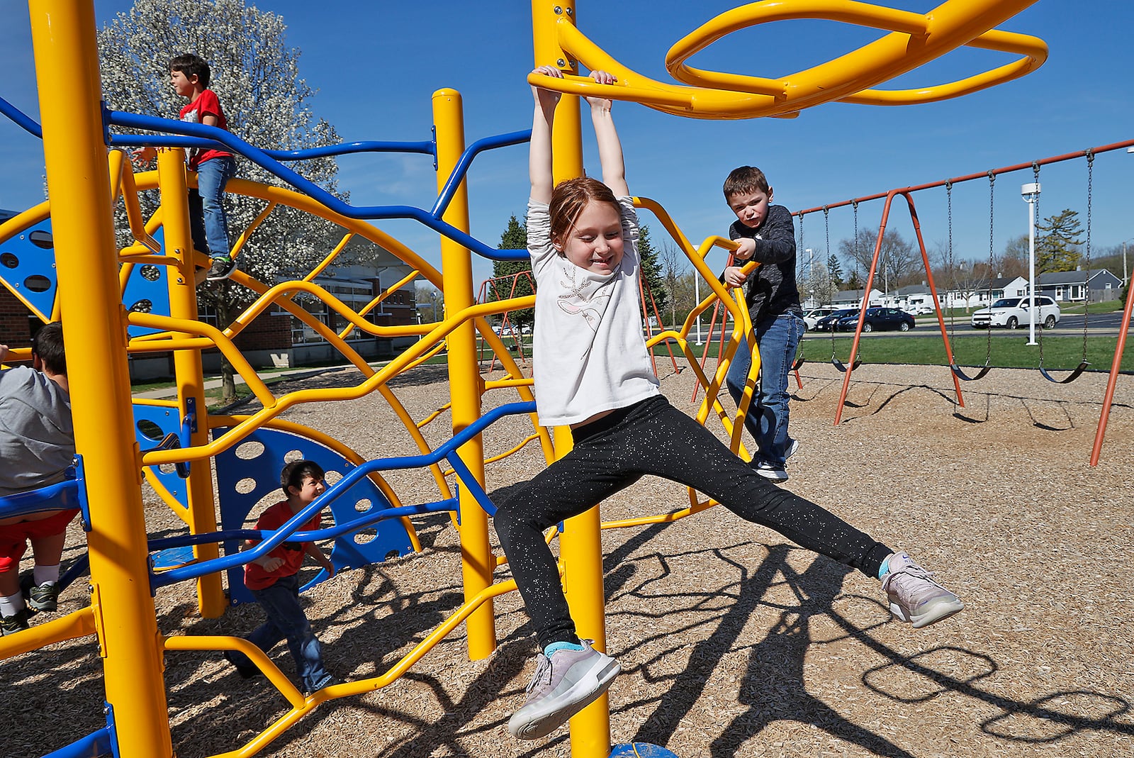 Children in the after school child care program at Springfield City Schools enjoy the sunshine and warm weather Monday, April 10, 2023 as they play on the playground at Horace Mann Elementary School until their parents pick them up. BILL LACKEY/STAFF