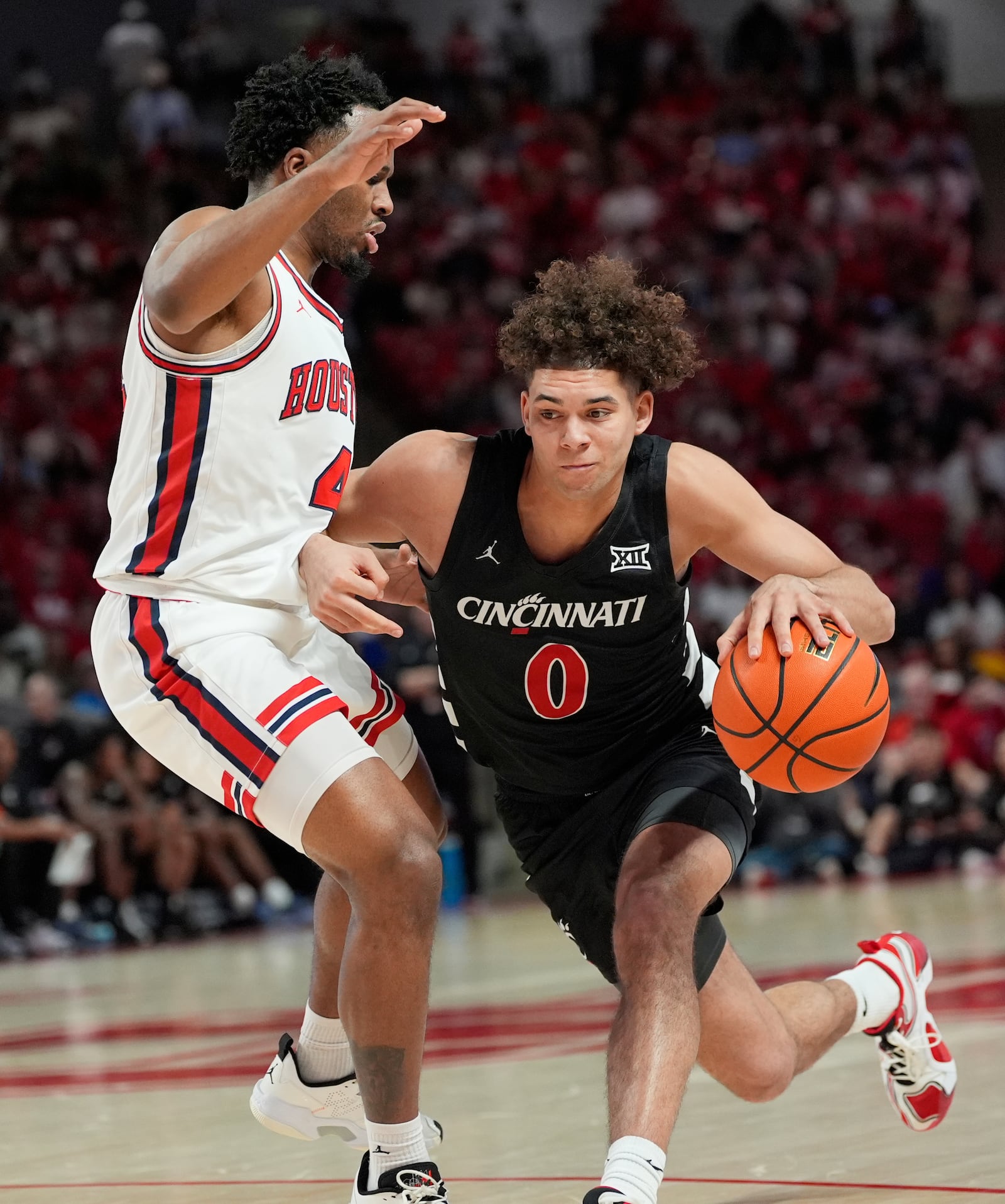 Cincinnati's Dan Skillings Jr. (0) drives toward the basket as Houston's L.J. Cryer (4) defends during the first half of an NCAA college basketball game Saturday, March 1, 2025, in Houston. (AP Photo/David J. Phillip)