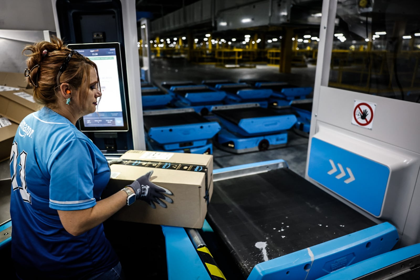 Amy Stuckey loads boxes onto robots that whisk products around Amazon's 2.8 million-square-foot Amazon Union Fulfillment Center. JIM NOELKER/STAFF