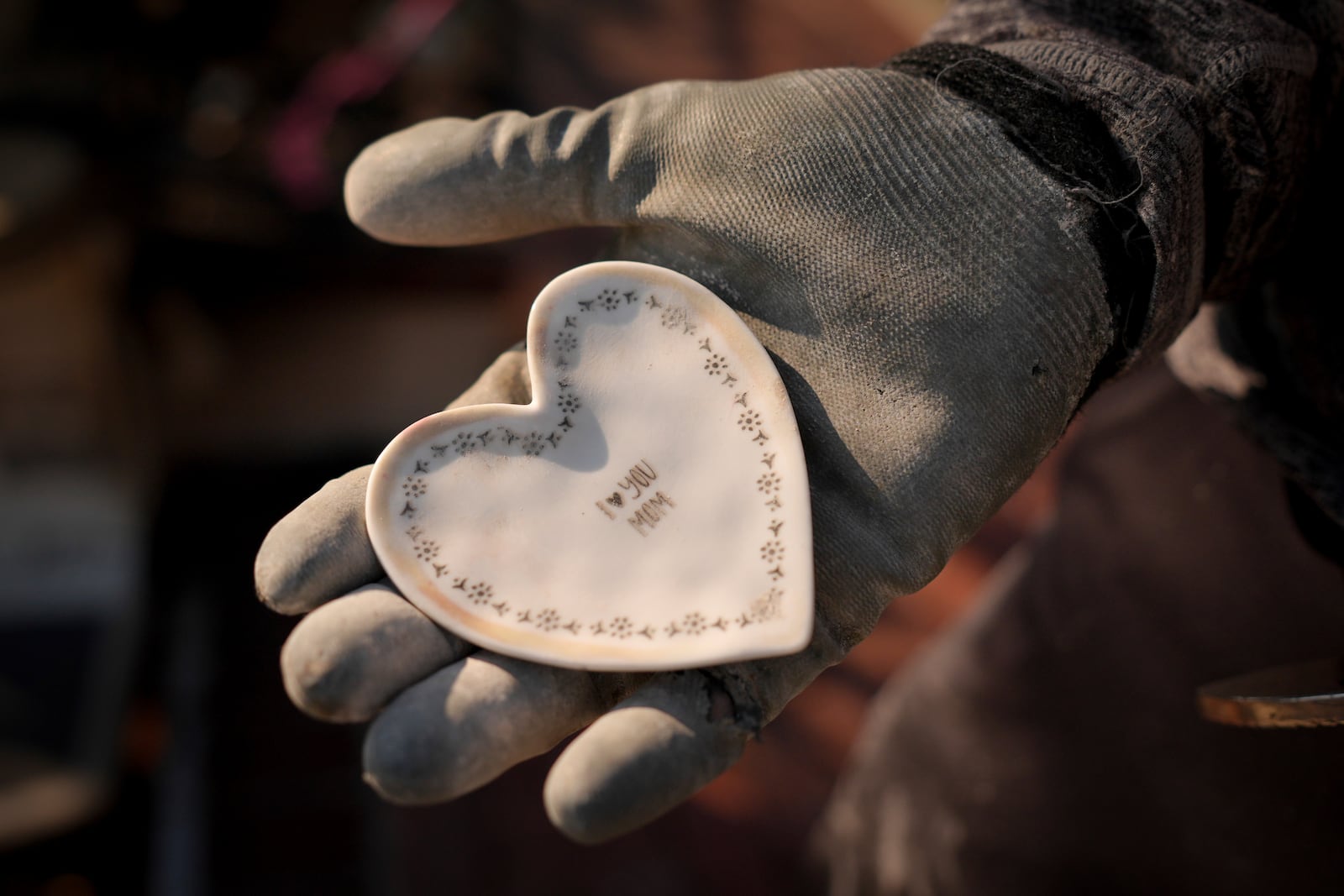 Tim Bearer holds a keepsake in his mother's fire-ravaged property in the aftermath of the Palisades Fire in the Pacific Palisades neighborhood of Los Angeles, Tuesday, Jan. 28, 2025. (AP Photo/Jae C. Hong)