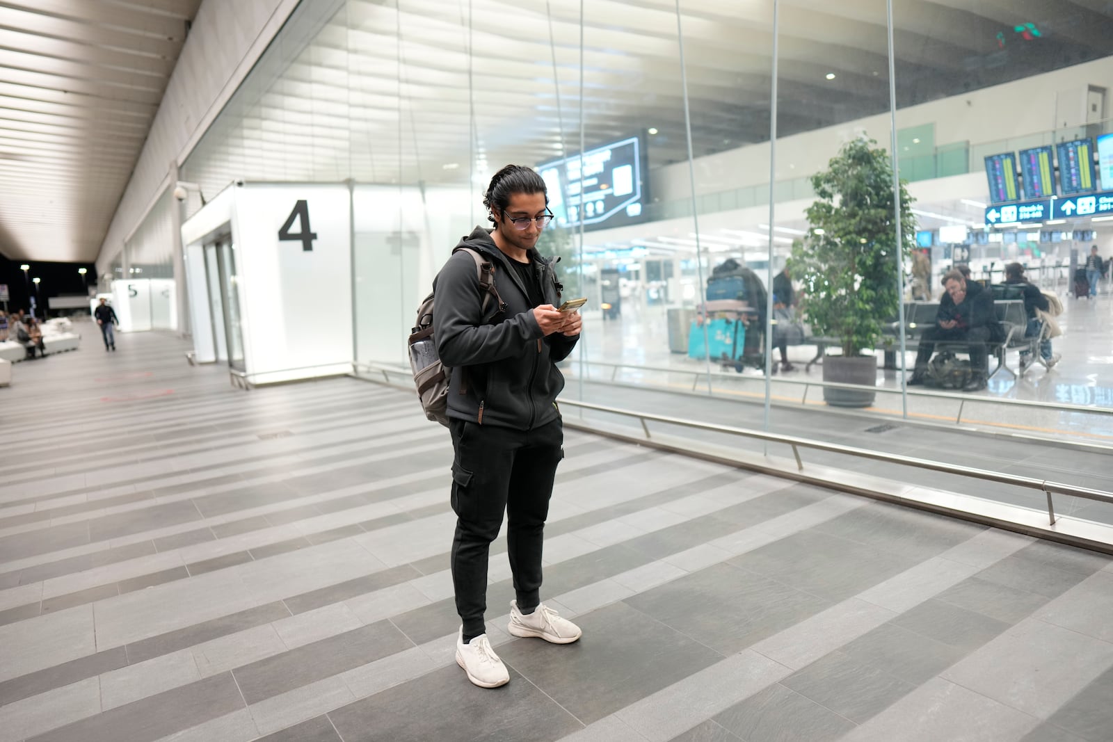 Miraj Chopra, passenger of American Airlines flight AA292 en route from New York to New Delhi that turned around over the Caspian Sea Sunday, Feb. 23, 2025, and landed at Rome's Leonardo da Vinci International airport checks his phone. (AP Photo/Bernat Armangue)