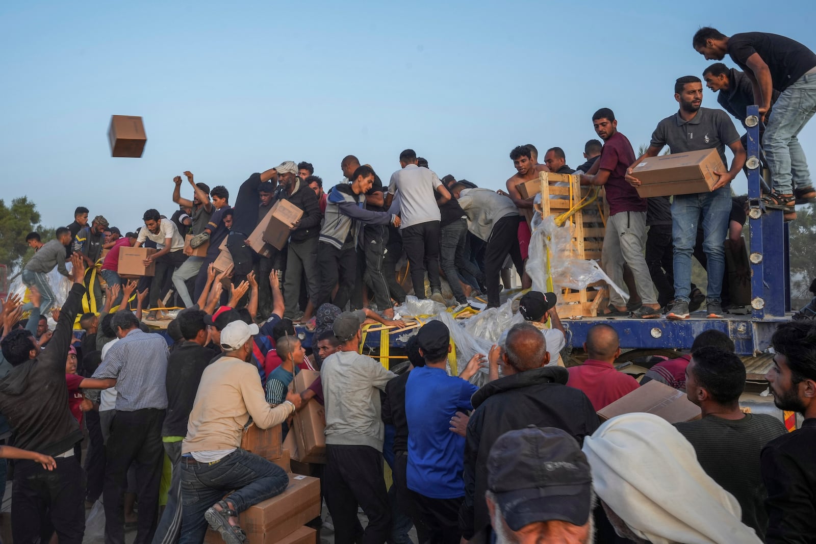 FILE - Palestinians storm trucks loaded with humanitarian aid brought in through a new U.S.-built pier, in the central Gaza Strip, on May 18, 2024. (AP Photo/Abdel Kareem Hana, File)