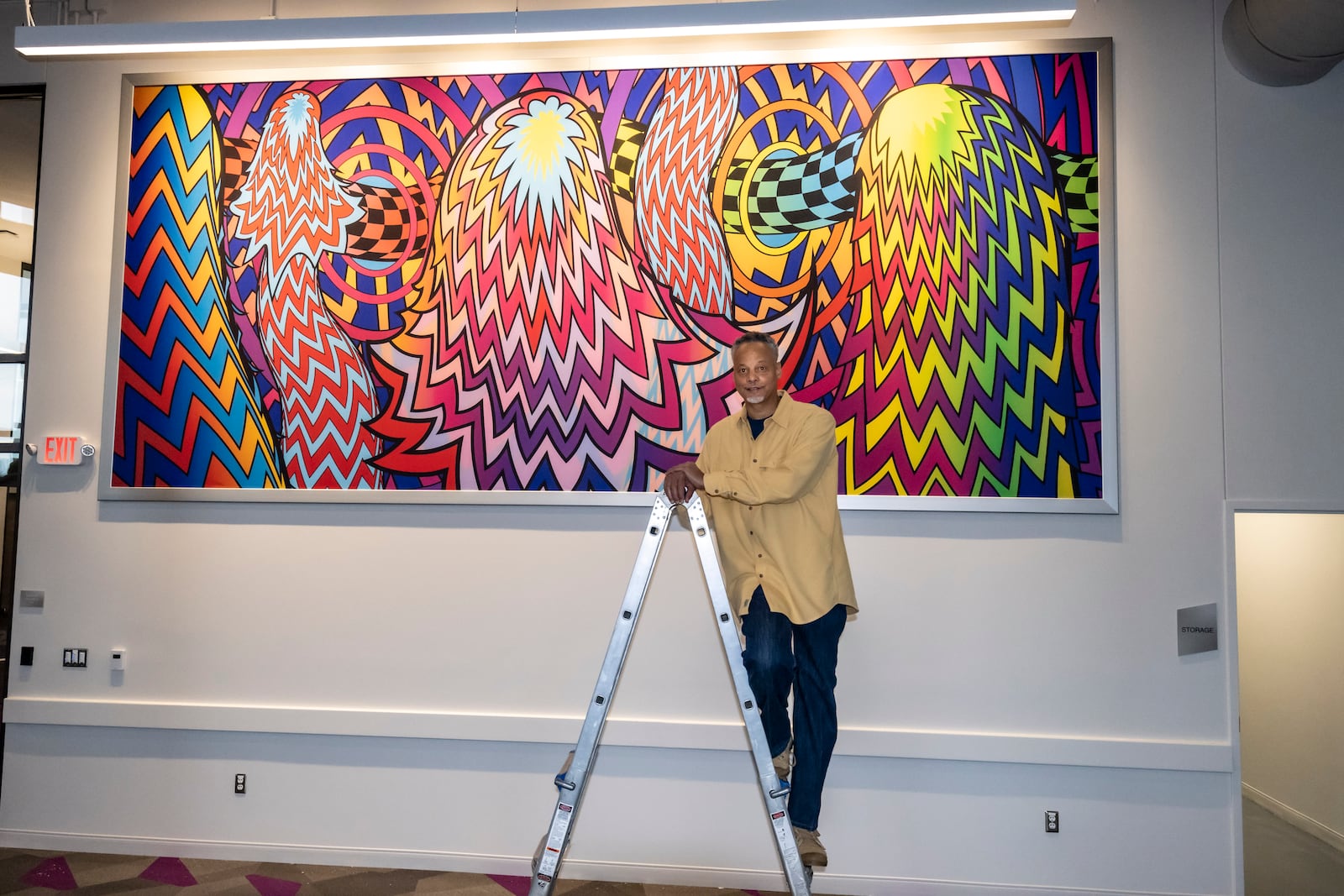 Kevin Harris is pictured with the mural he created for the Dayton Metro Library's West branch.