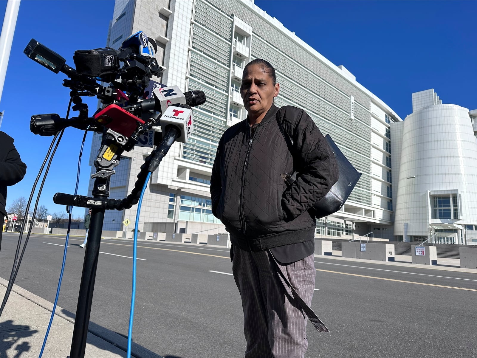 Elizabeth Alvarado, the mother of Nisa Mickens, a 15-year-old who was killed by MS-13 gang members in 2016, speaks outside the federal court, behind, in Central Islip, New York, where Jairo Saenz, a high-ranking member of a local MS-13 clique, pleaded guilty to racketeering and other federal charges on Tuesday, Jan. 14, 2025. (AP Photo/Philip Marcelo)