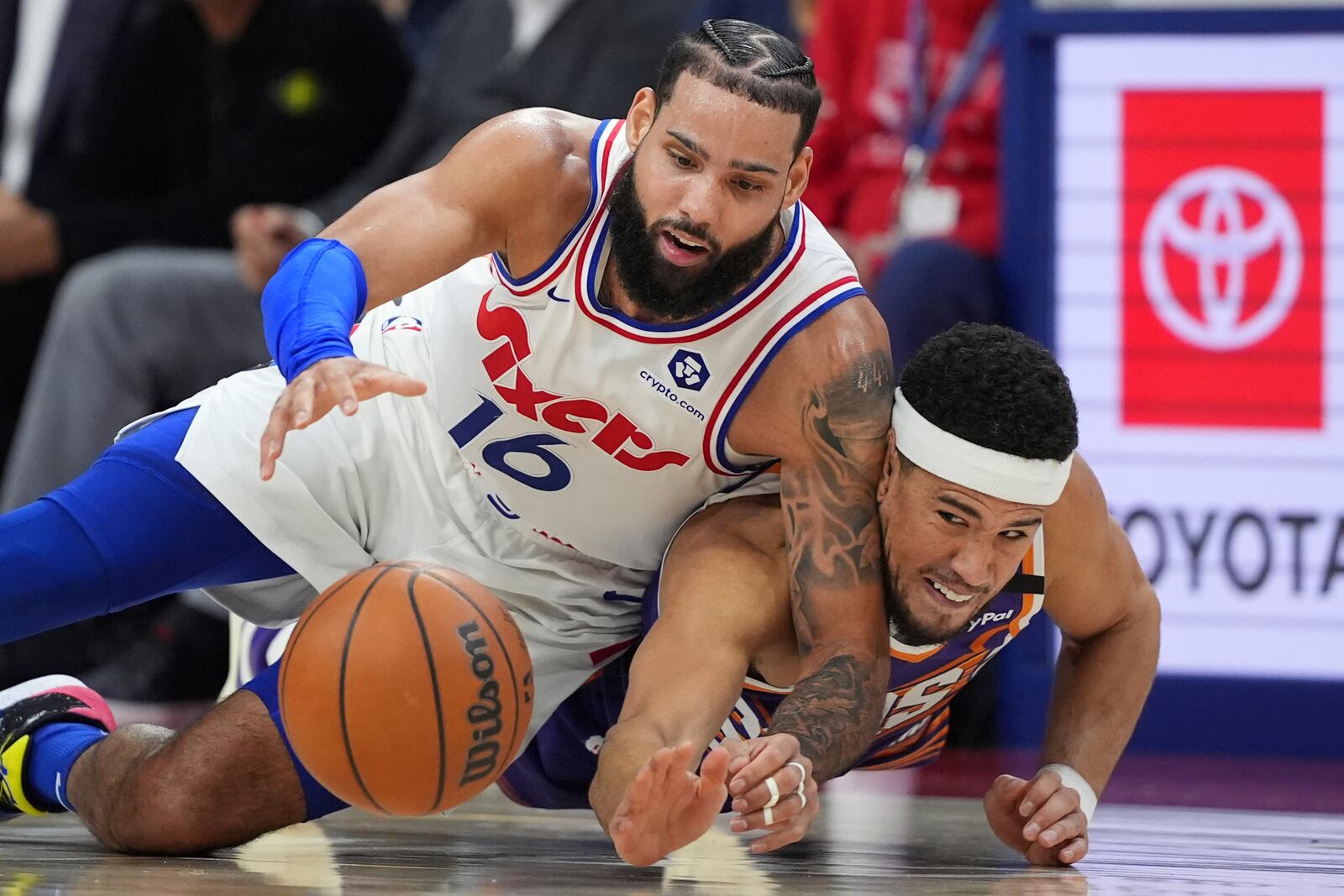 Philadelphia 76ers' Caleb Martin, left, and Phoenix Suns' Devin Booker struggle for a loose ball during the second half of an NBA basketball game, Monday, Jan. 6, 2025, in Philadelphia. (AP Photo/Matt Slocum)