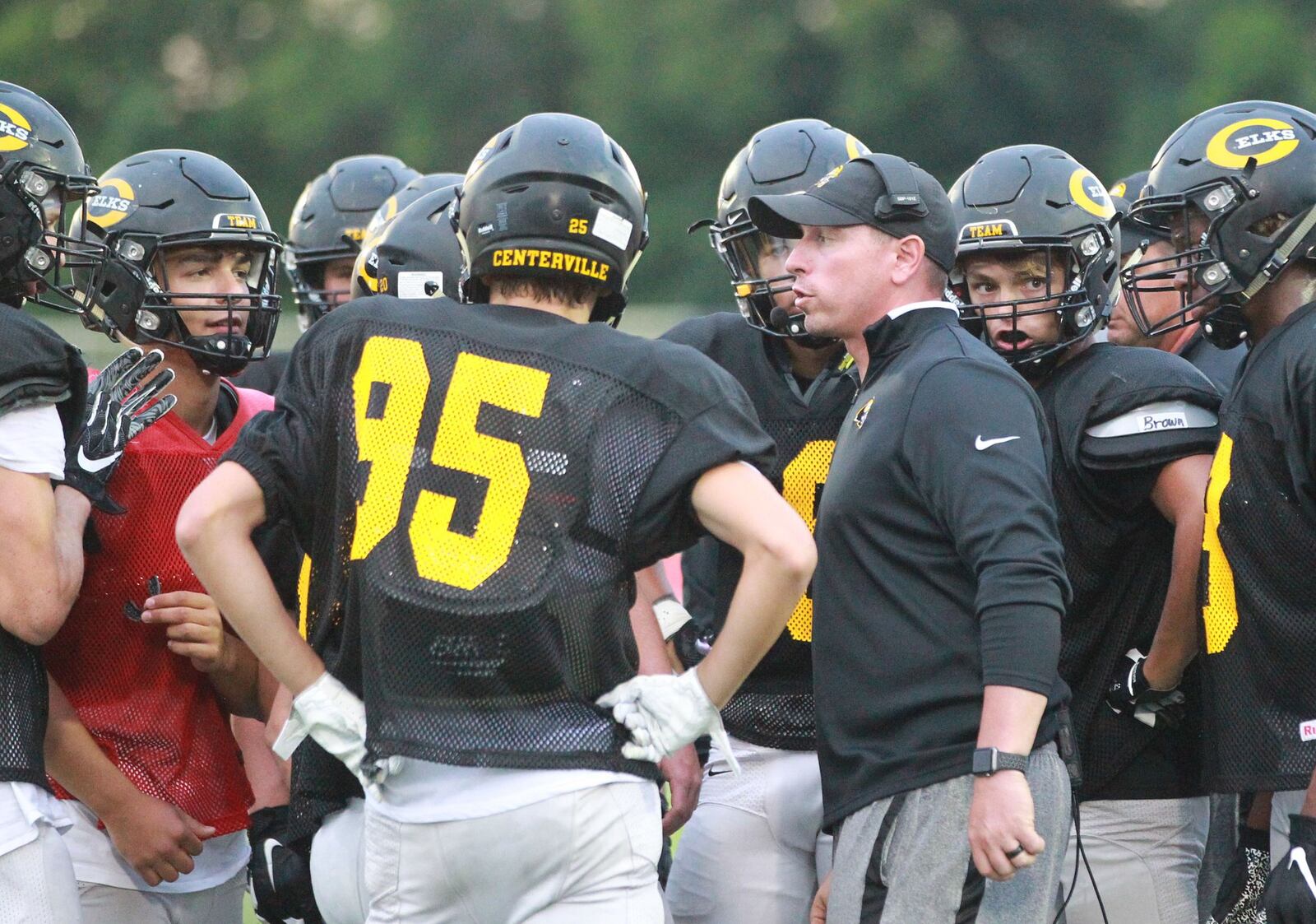 Centerville High School sophomore QB Chase Harrison (left) and the Elks huddle with head coach Brent Ullery at Trotwood-Madison in a football preseason scrimmage on Thursday, Aug. 22, 2019. MARC PENDLETON / STAFF