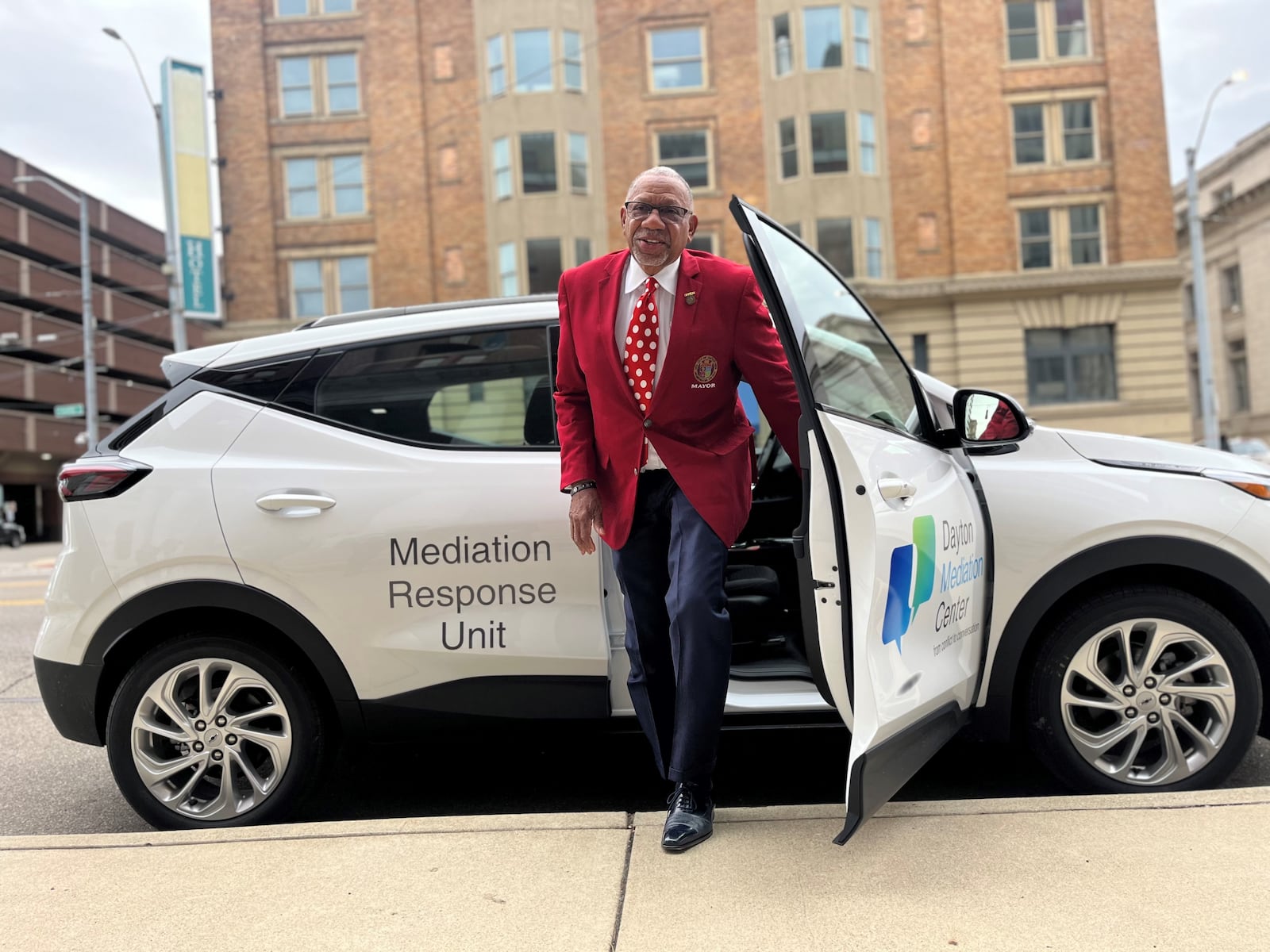 Dayton Mayor Jeffrey Mims Jr. shows off one of the city's first all-electric vehicles. The city has acquired five Chevrolet Volts and hopes to replace all 1,200 of its vehicles with electric cars and trucks by 2035. CORNELIUS FROLIK / STAFF