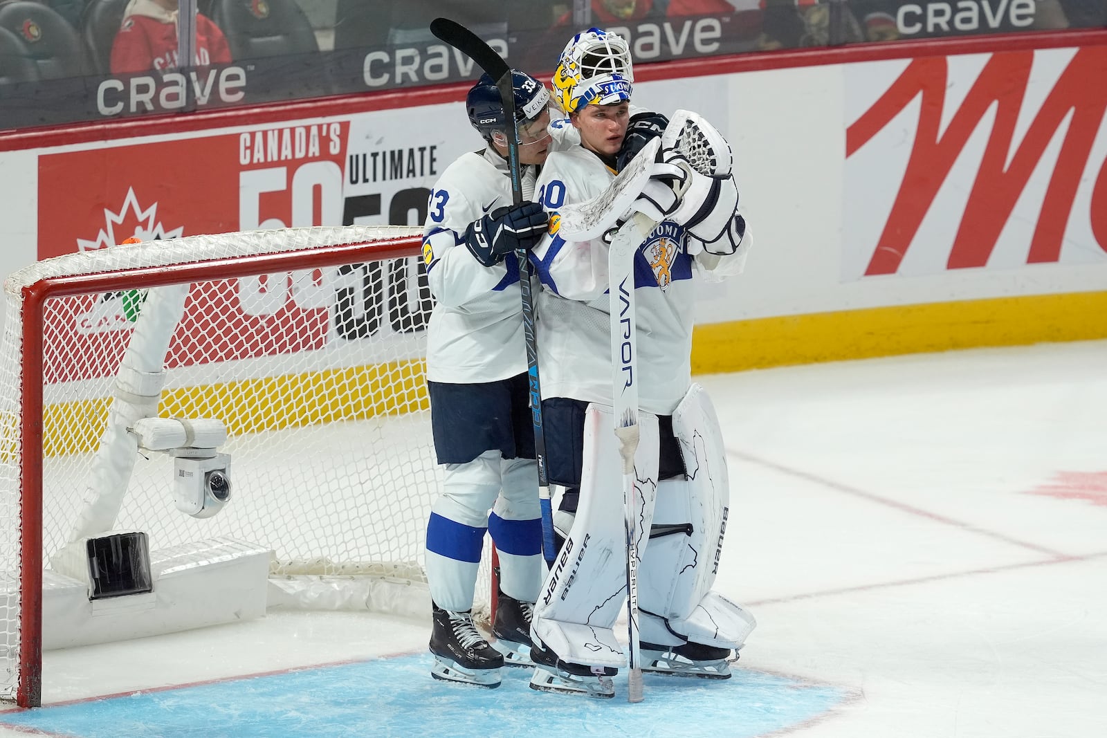 Finland defenseman Aron Kiviharju (33) consoles Finland goaltender Petteri Rimpinen (30) following their overtime loss to the United States in the IIHF World Junior Hockey Championship gold medal game in Ottawa, Ontario, Sunday, Jan. 5, 2025. (Adrian Wyld/The Canadian Press via AP)