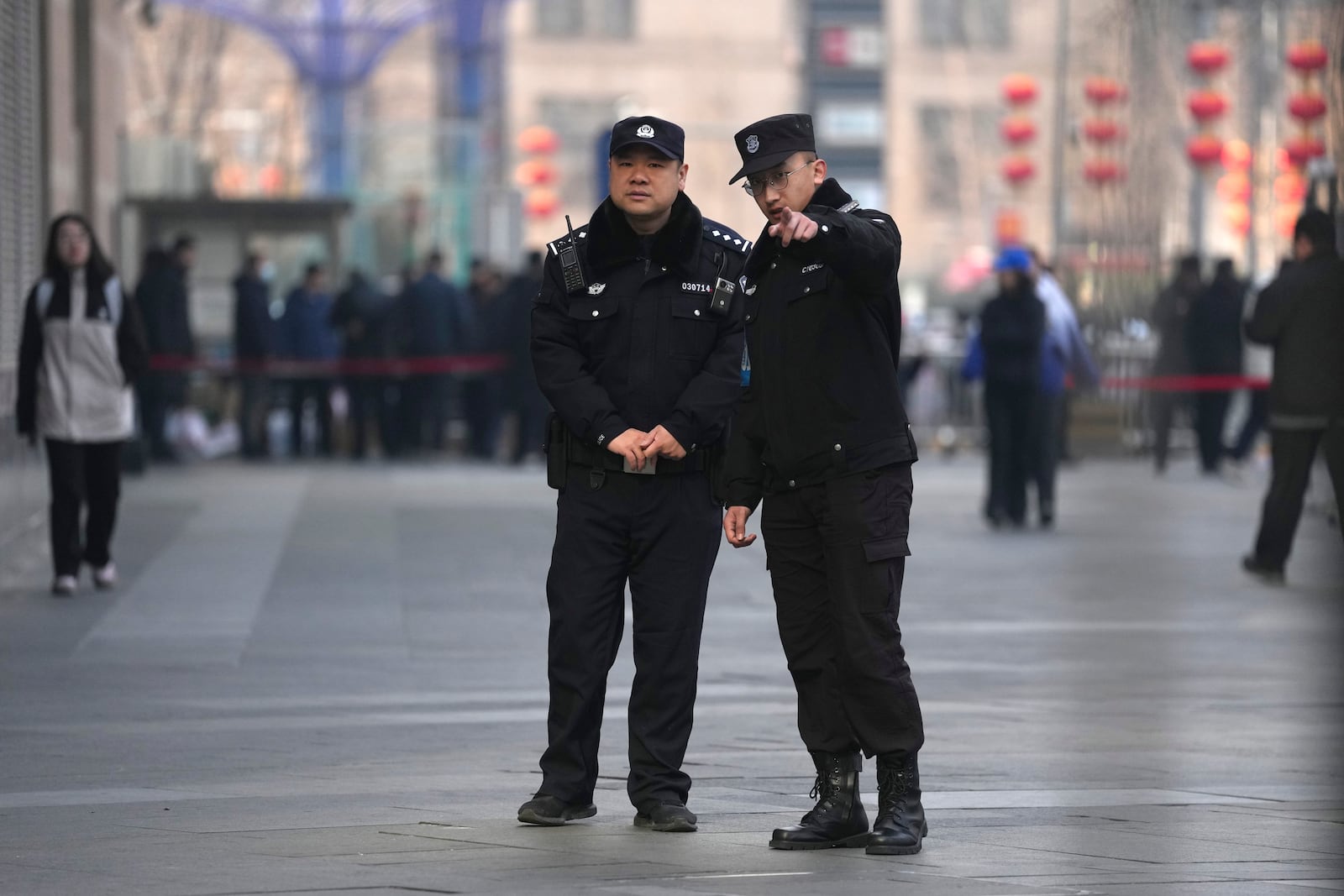 Chinese police officers monitor journalists gathered near a meeting of family members of passengers who were on board the MH370 Malaysia Airline jet that went missing in 2014 in Beijing, China, Saturday, March 8, 2025. (AP Photo/Ng Han Guan)