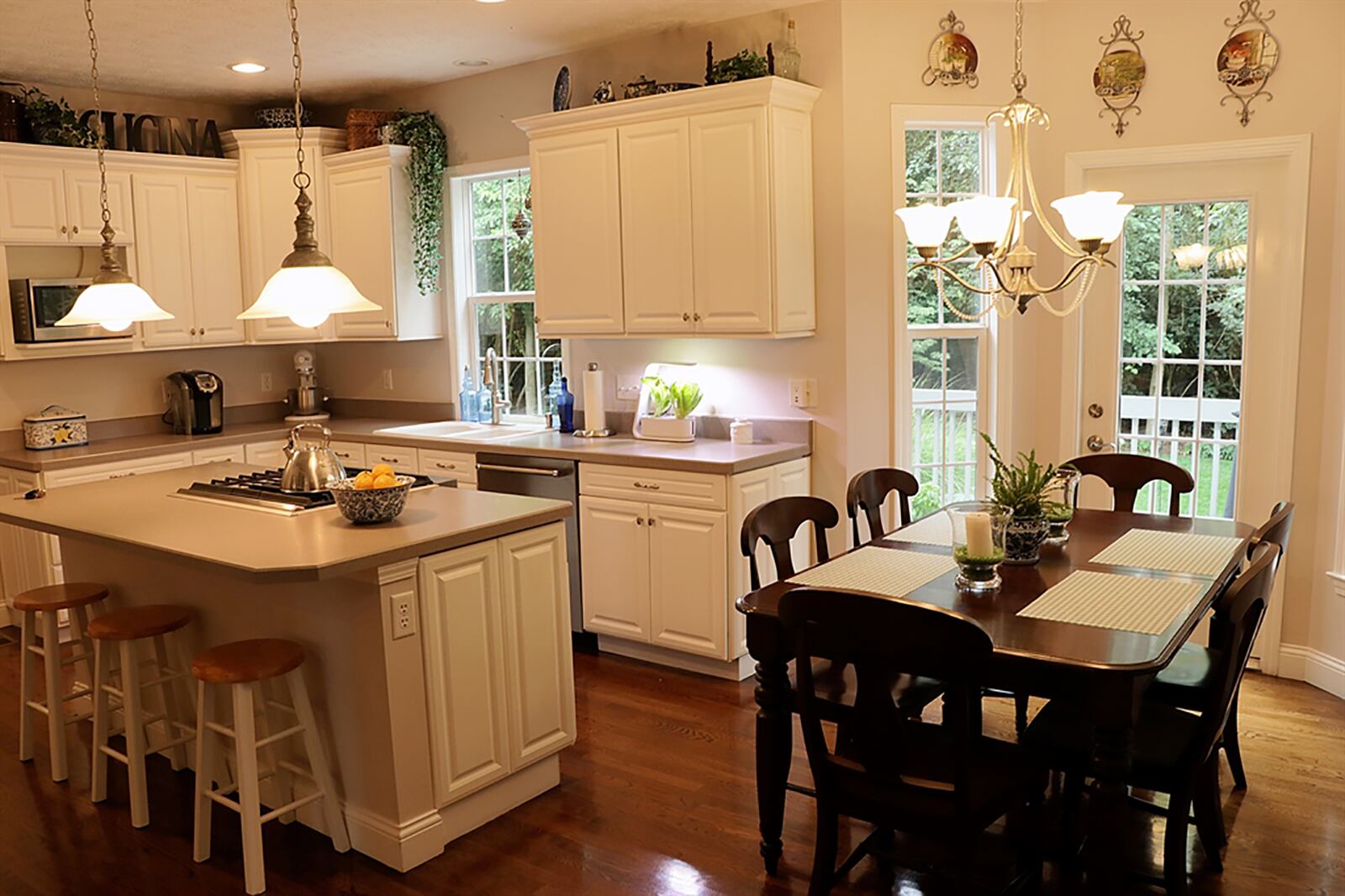 White cabinets and light countertops fill the kitchen, offering plenty of work space. An island has a gas range and seating for up to four. A window is above the double sink, and double doors open to a pantry closet. CONTRIBUTED PHOTO BY KATHY TYLER