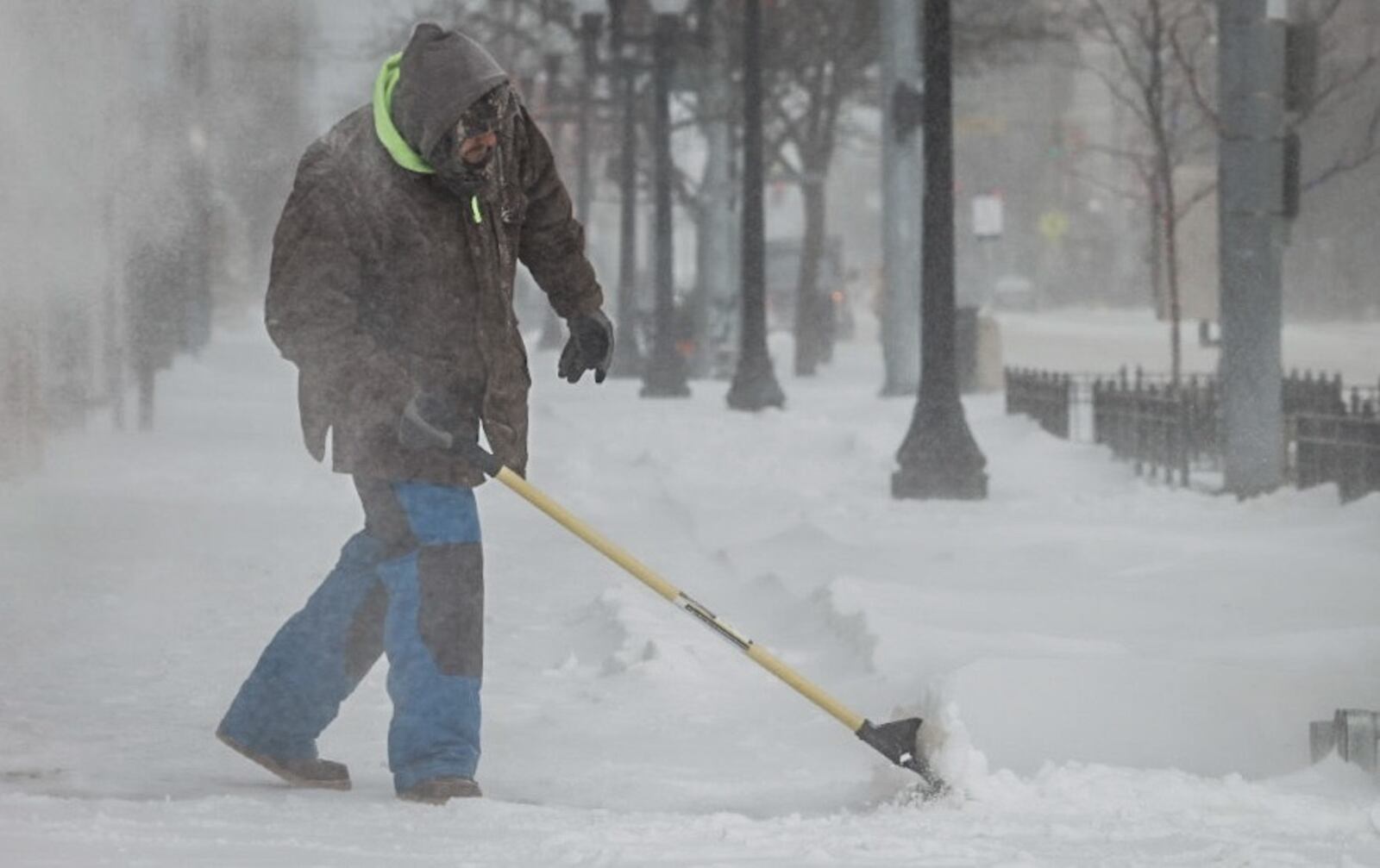 Salvador Arenas shovels snow on Main Street in downtown Dayton  Friday December 23, 2022. Jim Noelker/Staff