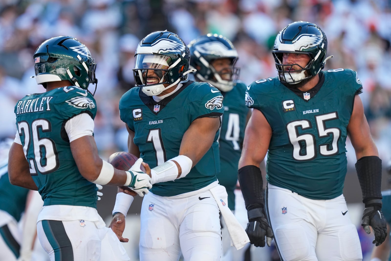 Philadelphia Eagles quarterback Jalen Hurts (1) hands the ball to running back Saquon Barkley (26) after Hurts scored a touchdown against the Cincinnati Bengals during the second half of an NFL football game, Sunday, Oct. 27, 2024 in Cincinnati. Eagles' Lane Johnson (65) looks on. The Eagles won 37-17. (AP Photo/Carolyn Kaster)