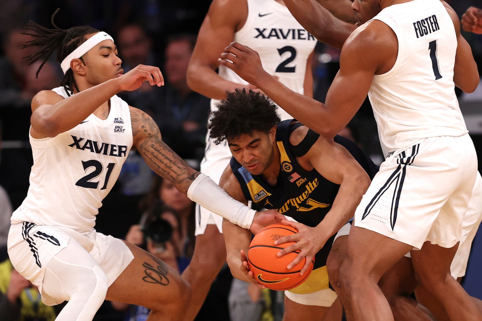 Xavier guard Dante Maddox Jr. (21) and Marcus Foster (1) attempt to steal the ball from Marquette guard Stevie Mitchell (4) during the first half of an NCAA college basketball game in the quarterfinals of the Big East Conference tournament, Thursday, March 13, 2025, in New York. (AP Photo/Pamela Smith)