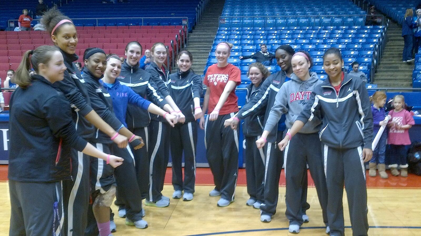 The players on the 2012-13 Dayton Flyers women's basketball team display their pink FORT bracelets honoring Melissa Fortener McLaughin, who died of breast cancer in 2009. Melissa's parents began to follow the Flyers women thanks to Cassie Sant (fifth from left in photo) who won the first B POSITIVE award honoring Melissa when she was a Fairmont High player. The bond between the Forteners and UD women's basketball continues today.  CONTRIBUTED