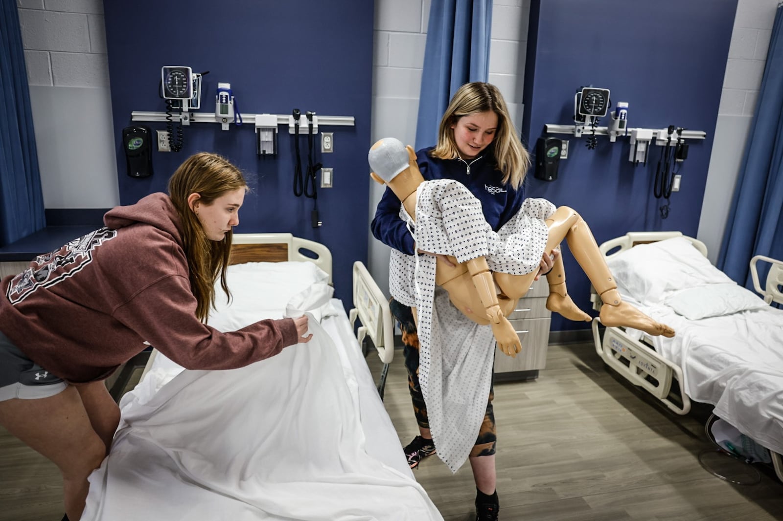 Fairmont High School juniors Devyn Teeple, left and Justice Michels move a mannequin used in training future nurses. The students are participating in the STNA program which trains high school students to become nurses. JIM NOELKER/STAFF