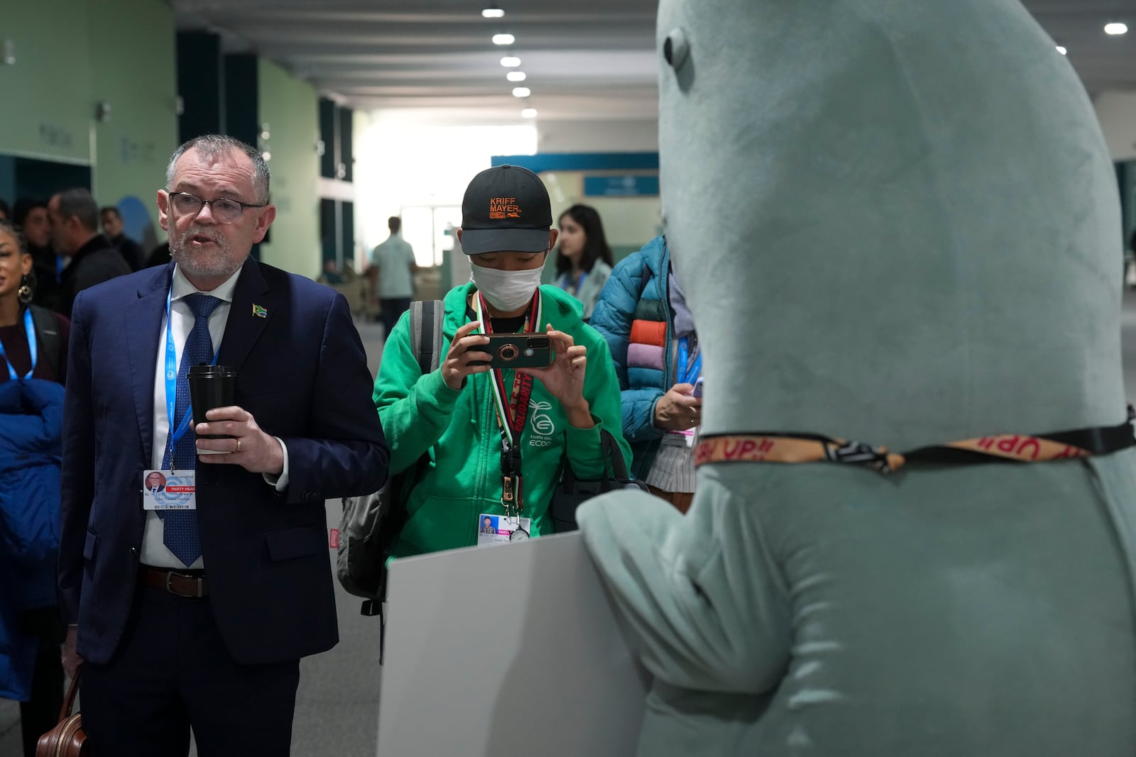 Dion George, South Africa environment minister, left, walks past a person in a dugong costume during the COP29 U.N. Climate Summit, Friday, Nov. 22, 2024, in Baku, Azerbaijan. (AP Photo/Peter Dejong)