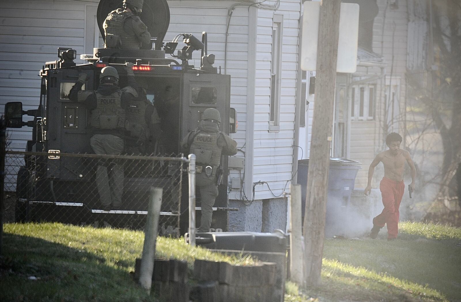 A man involved in a standoff with Dayton police ran past one SWAT team with a gun in his hand after those officers had deployed tear gas into a house Tuesday, Dec. 14, 2021. The 21-year-old man, identified as William Gardner, ran toward a second SWAT team and vehicle, not shown in this photo. Seconds later, he was shot and killed, according to Interim Police Chief Matt Carper. Carper said Gardner earlier Tuesday had shot and wounded a man in the leg and shot the man’s dog as they walked by the house, then Gardner refused to come out of the house for hours. MARSHALL GORBY/STAFF