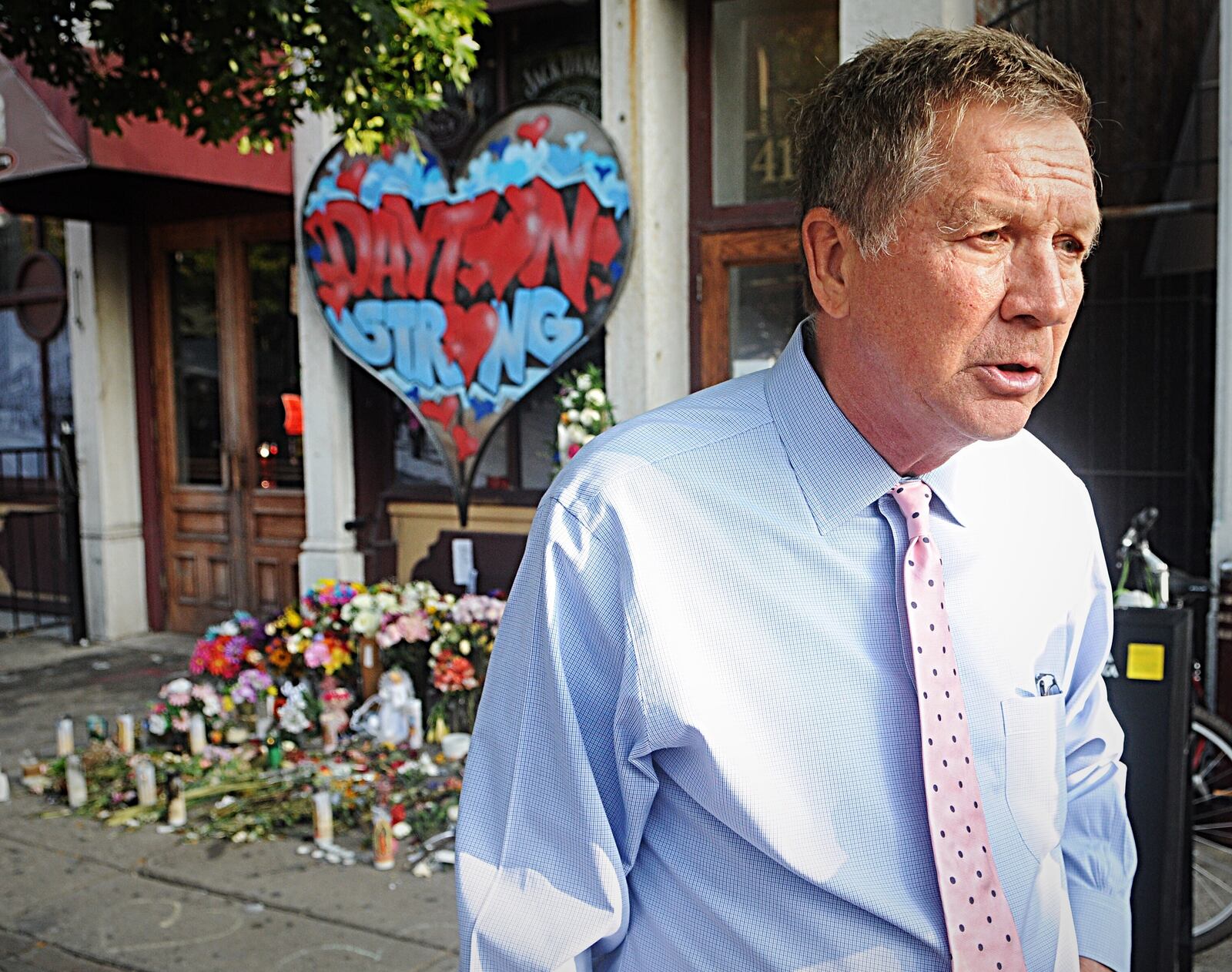 Former Ohio Governor John Kaisch addresses reporters in the Oregon District, behind a memorial for the victims of Sunday's mass shooting that killed nine victims. (MARSHALL GORBY/STAFF)