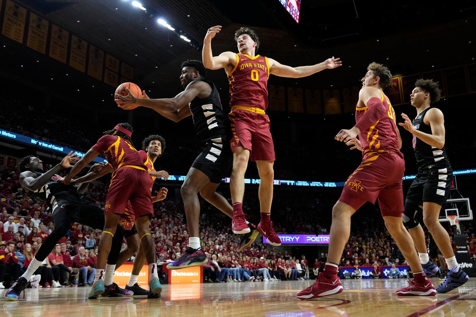 Cincinnati guard Josh Reed grabs a rebound in front of Iowa State guard Nate Heise (0) during the first half of an NCAA college basketball game Saturday, Feb. 15, 2025, in Ames, Iowa. (AP Photo/Charlie Neibergall)