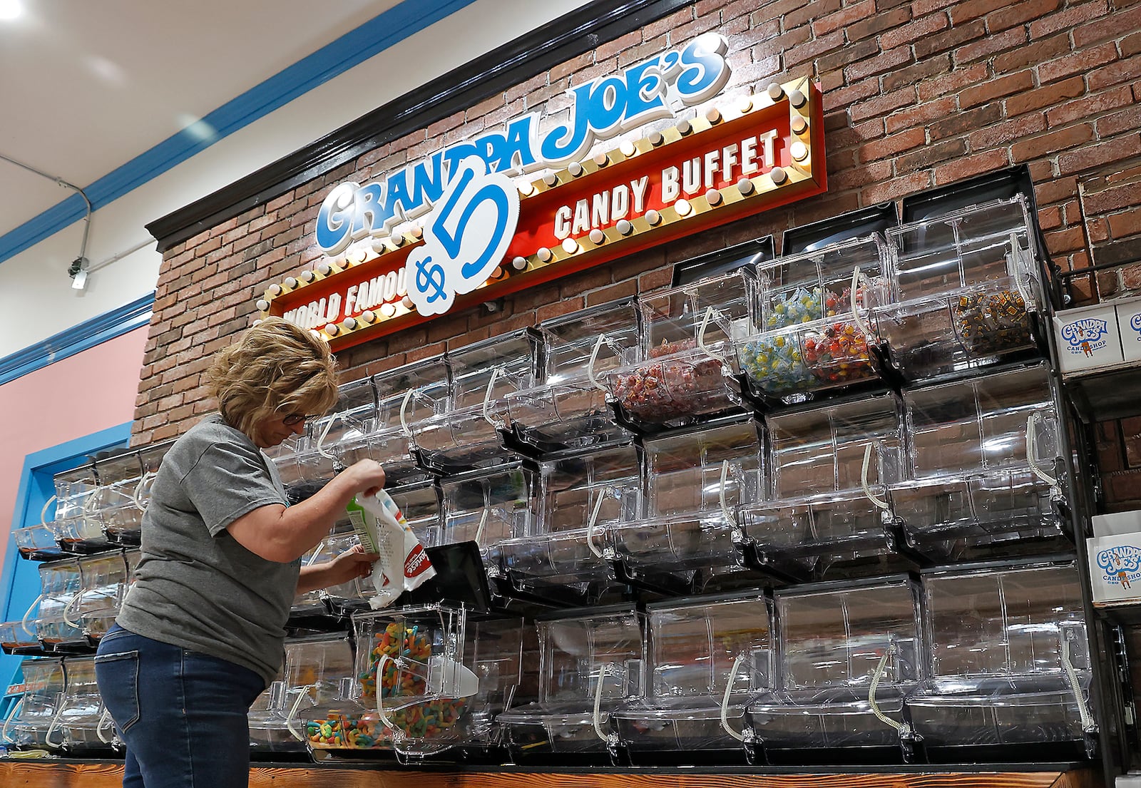 Heidi Heminger stocks the candy in Grandpa Joe's World Famous Candy Buffet Monday, Nov. 14, 2022 as the store employees get ready for their grand opening in Springfield. BILL LACKEY/STAFF