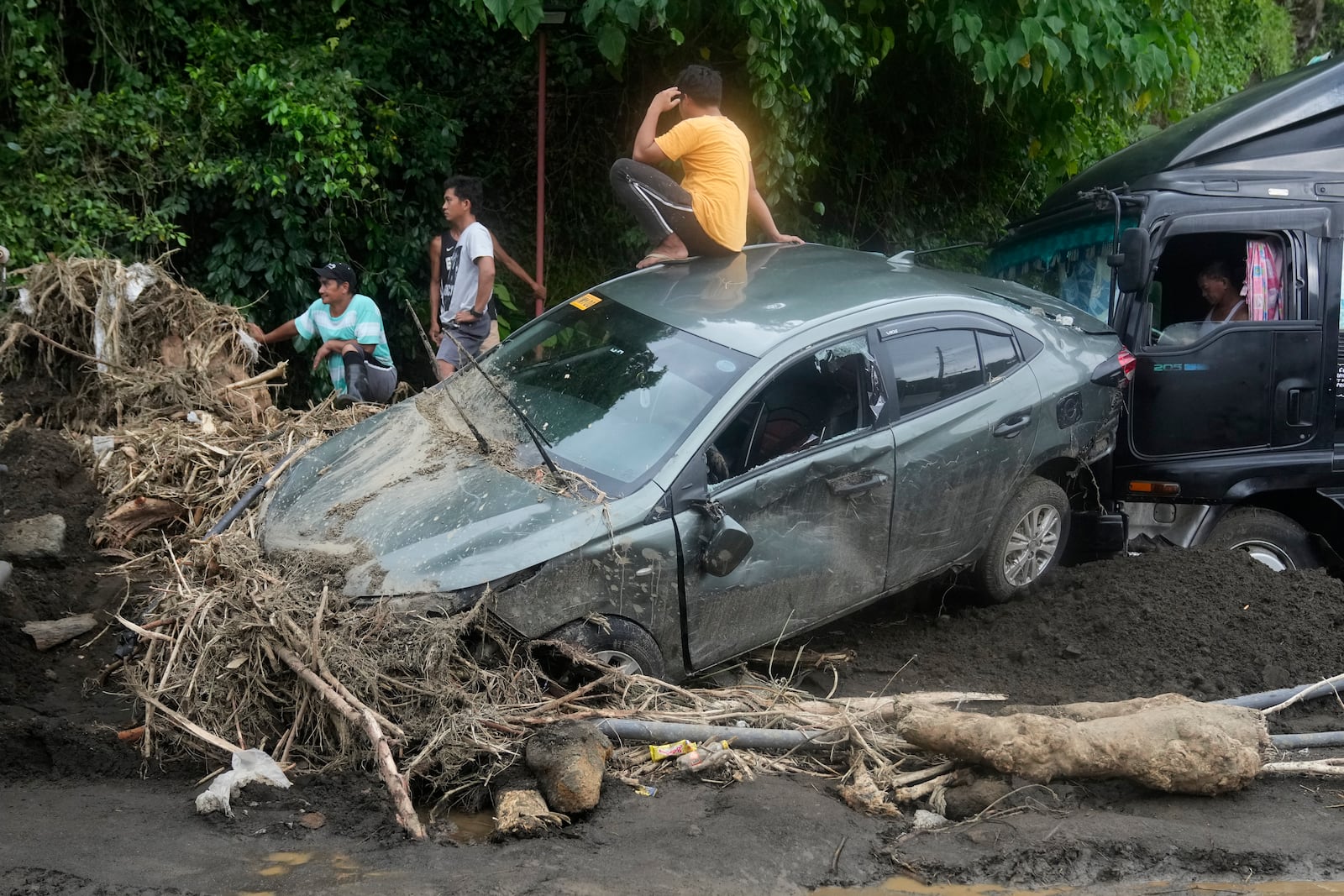 A man sits on a damaged car after a landslide triggered by Tropical Storm Trami in Talisay, Batangas province, Philippines, Saturday, Oct. 26, 2024. (AP Photo/Aaron Favila)