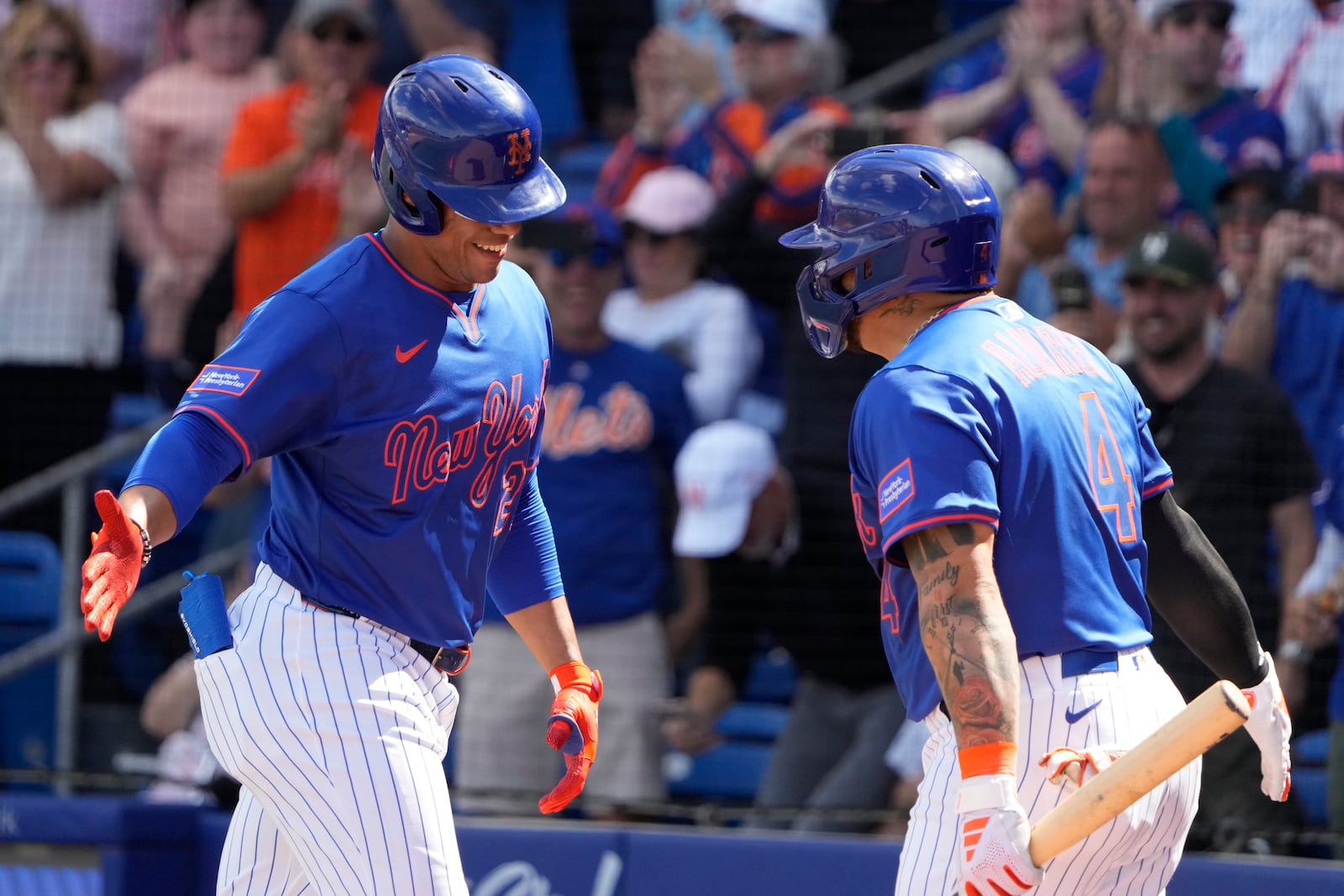 New York Mets' Juan Soto, left, is congratulated by teammate Francisco Alvarez (4) after hitting a solo home run during the first inning of a spring training baseball game against the Houston Astros Saturday, Feb. 22, 2025, in Port St. Lucie, Fla. (AP Photo/Jeff Roberson)