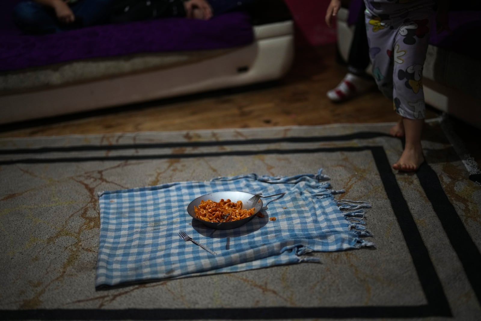 A plate of pasta sits on a tablecloth in the Sahin family's one-room apartment in the Tarlabasi neighborhood in Istanbul, Turkey, Wednesday, Dec. 4, 2024. (AP Photo/Francisco Seco)