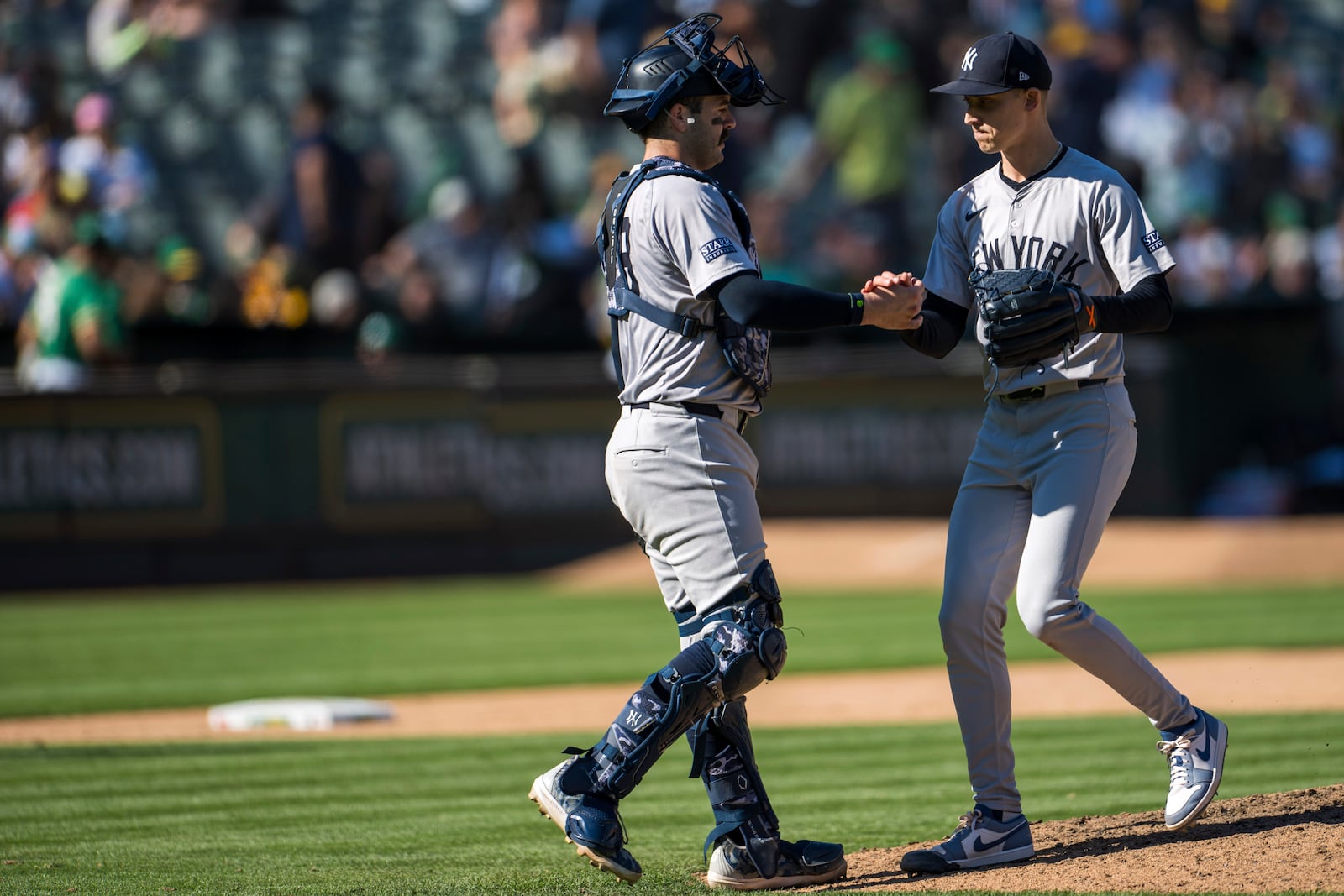 New York Yankees catcher Austin Wells, left, celebrates a win with pitcher Luke Weaver after a baseball game against the Oakland Athletics in Oakland, Calif., Sunday, Sept. 22, 2024. (AP Photo/Nic Coury)