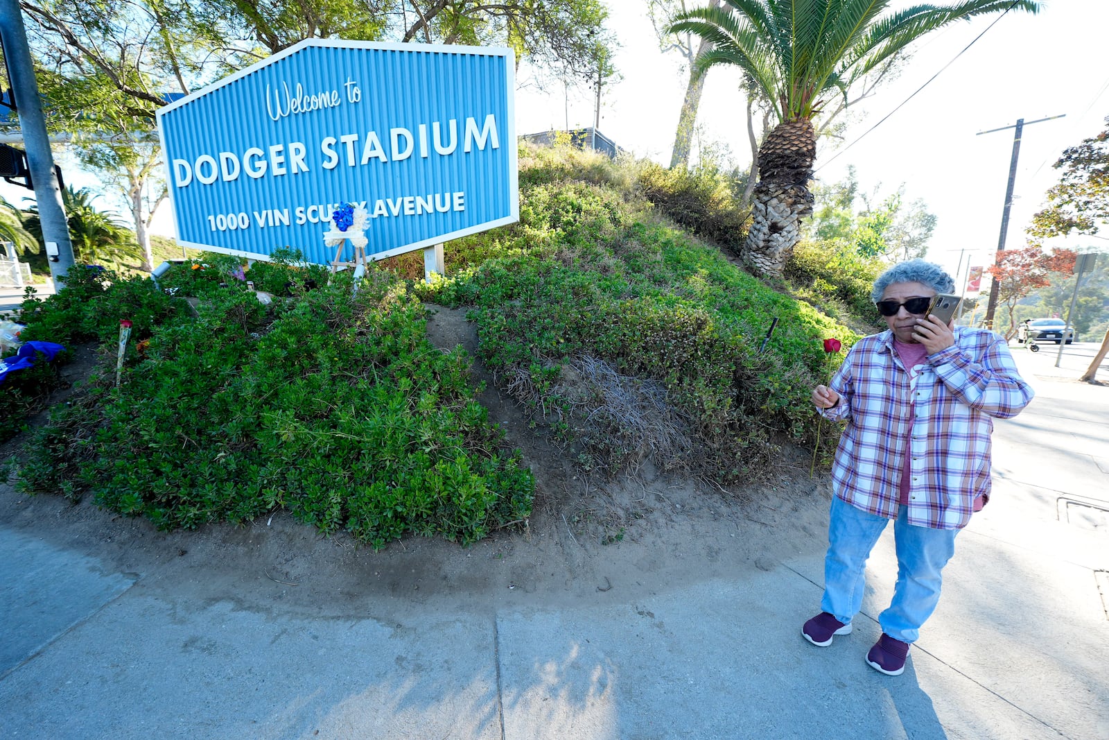 Gladys Sarmiento drops off a rose outside of Dodger Stadium after the death of former Dodgers pitcher Fernando Valenzuela, Wednesday, Oct. 23, 2024, in Los Angeles. (AP Photo/Julio Cortez)