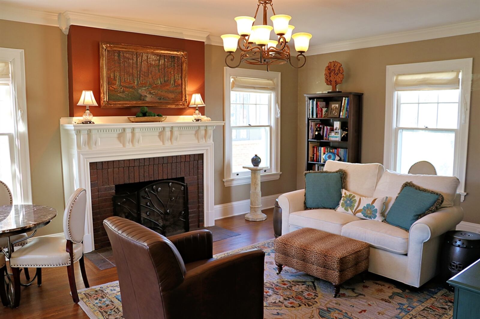 The centerpiece to the living room is a brick fireplace with a dentil wood mantel and tile hearth. Large windows flank the fireplace and are framed by white bold molding, which match the double-crown molding. 