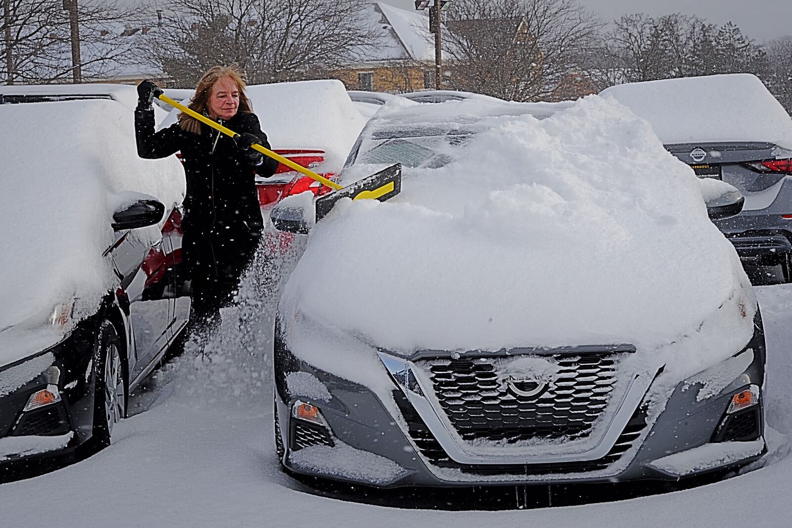 Cathy Baer, a sales representative at Matt Castrucci Auto Mall, clears several inches of snow from the cars on the lot Tuesday morning, February 16, 2021. MARSHALL GORBY\STAFF