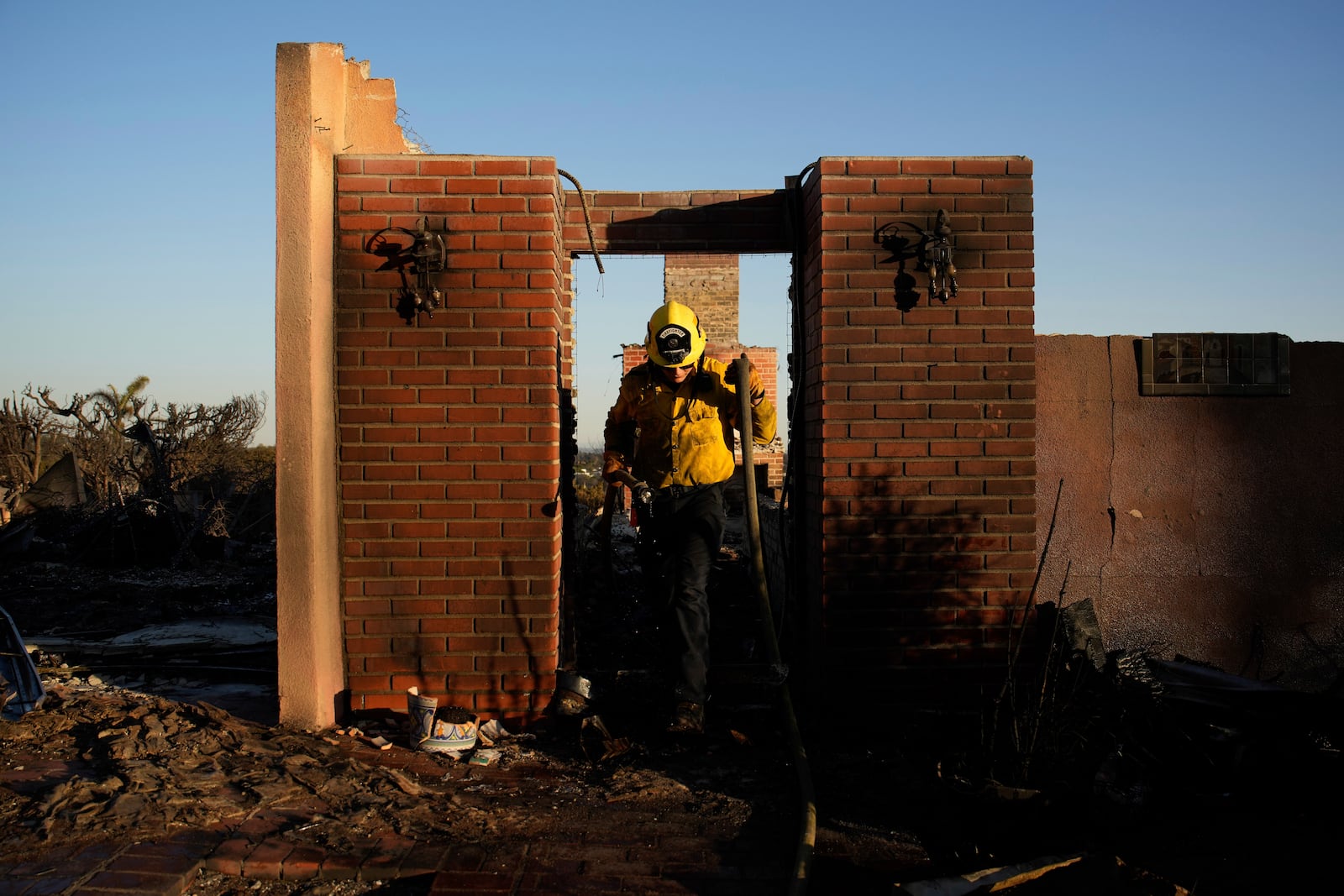 Apple Valley Fire District firefighter Wyatt Cortez walks through a destroyed house as he puts out hotspots from the Palisades Fire in the Pacific Palisades neighborhood of Los Angeles, Monday, Jan. 13, 2025. (AP Photo/John Locher)