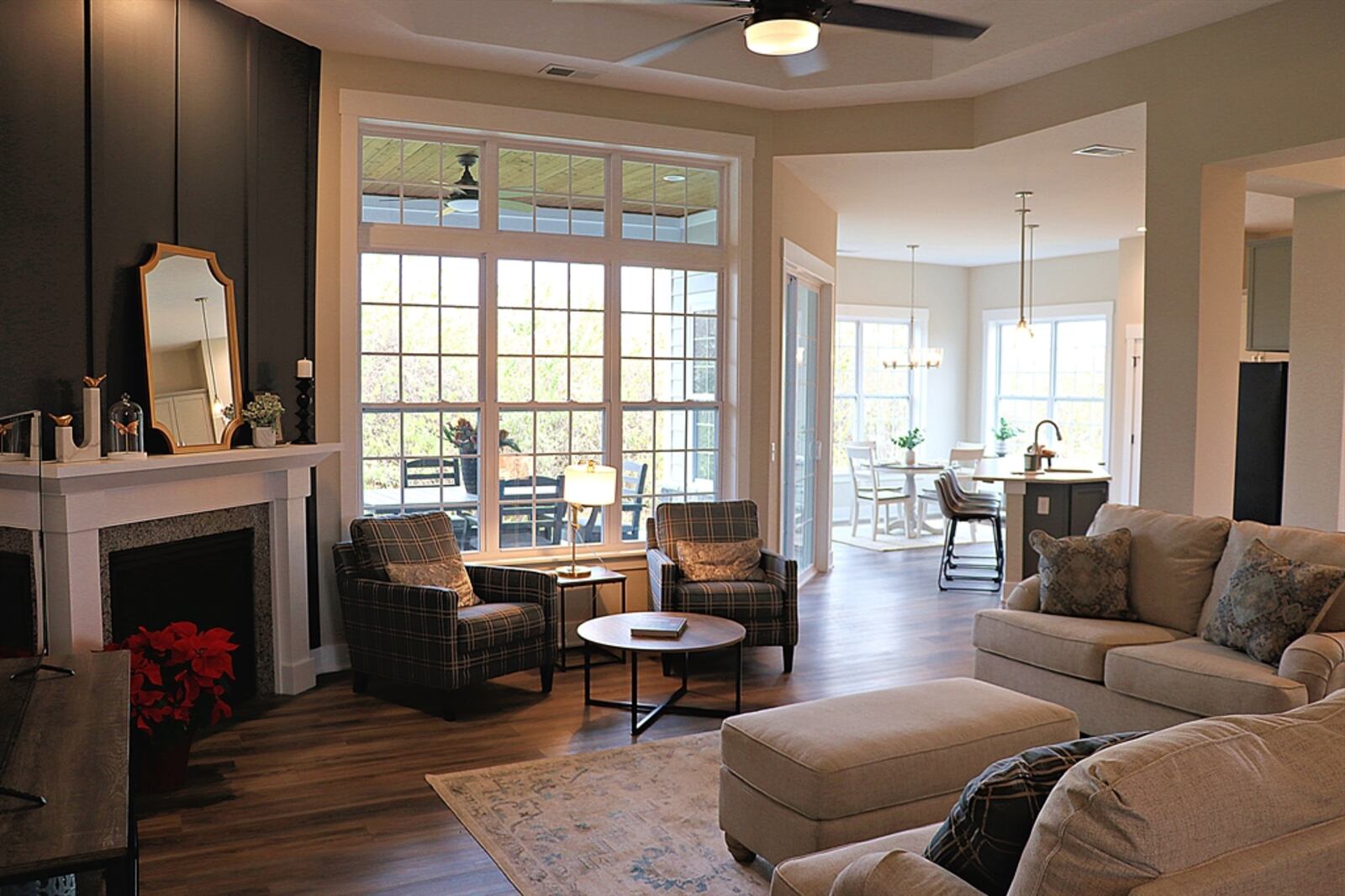 Tucked into one corner of the great room is a gas fireplace with a wood mantel and detailed woodwork. Triple windows look out over the covered backyard patio.