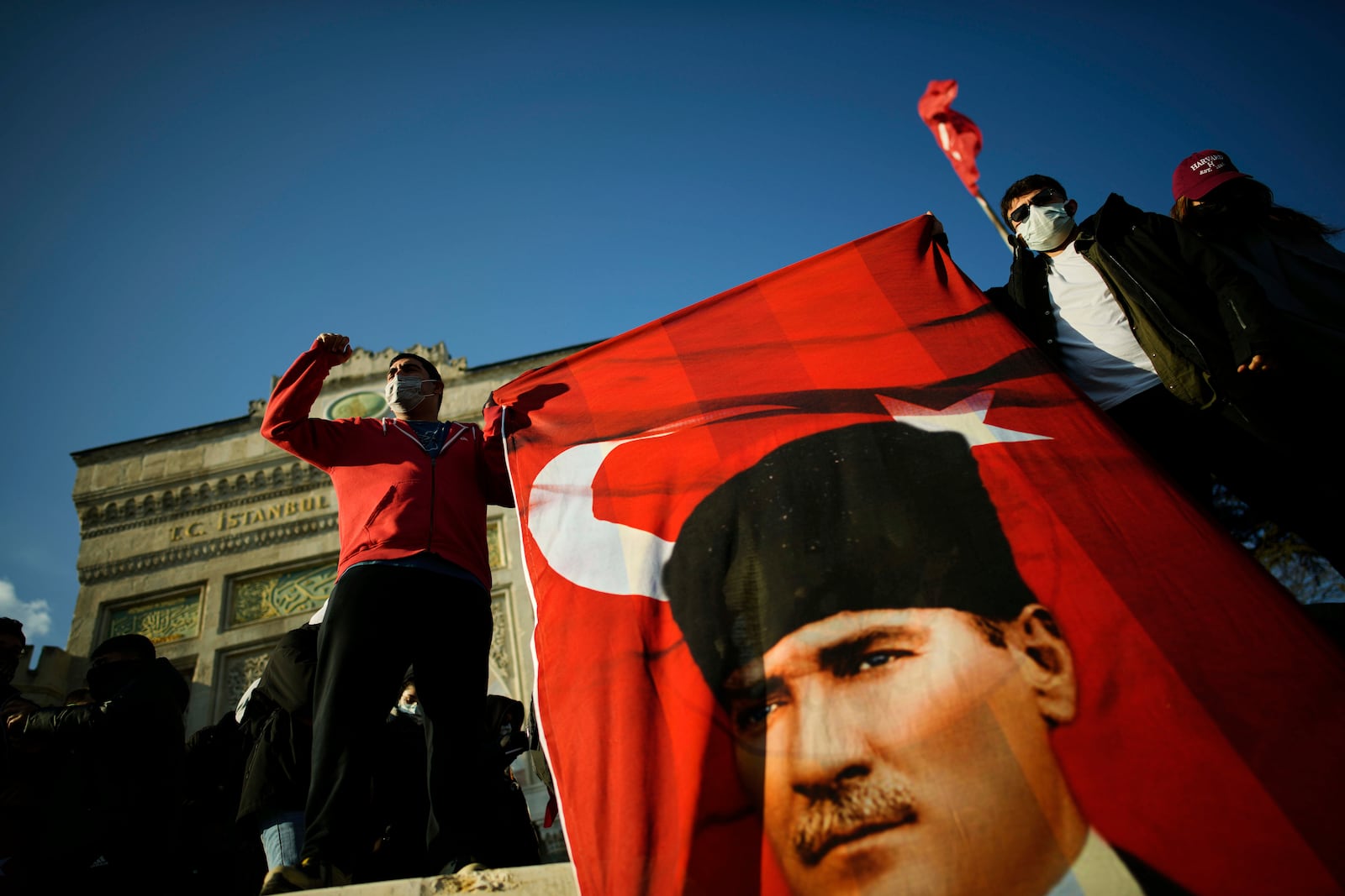 University students hold a Turkish flag with the image of Turkey's founding father Mustafa Kemal Ataturk, in Istanbul, Turkey, Friday, March 21, 2025, as they protest the arrest of Istanbul's Mayor Ekrem Imamoglu. (AP Photo/Emrah Gurel)