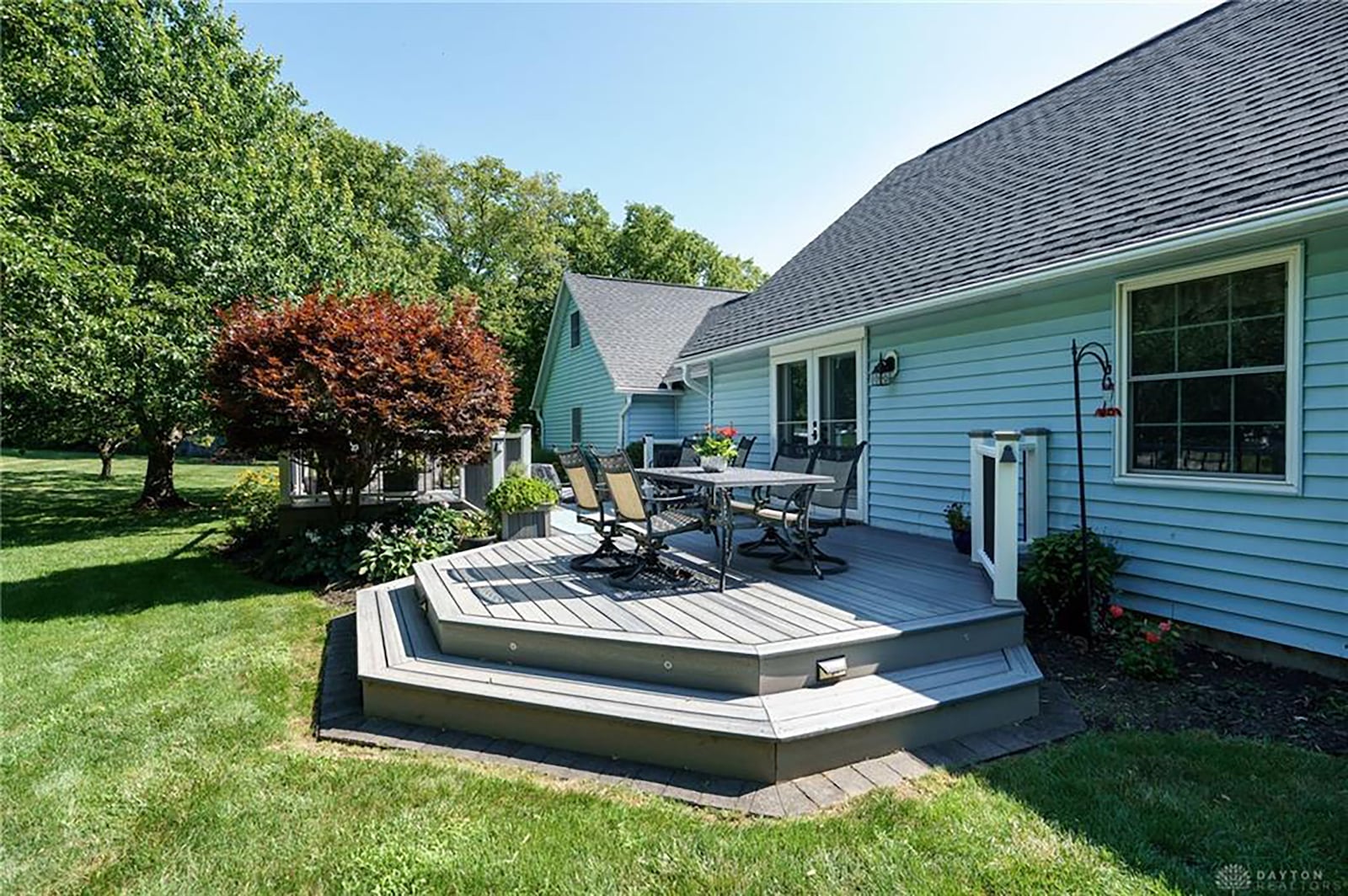 The rear of the home has a vinyl deck with steps and some railings and a paver patio.