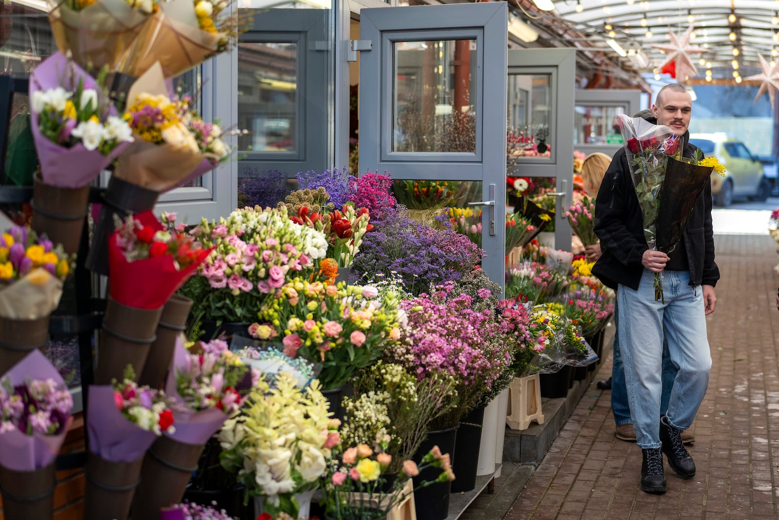 A man carries a bouquet of fresh flowers from a flower market on International Women's Day, in Vilnius, Lithuania, Saturday, March 8, 2025. (AP Photo/Mindaugas Kulbis)