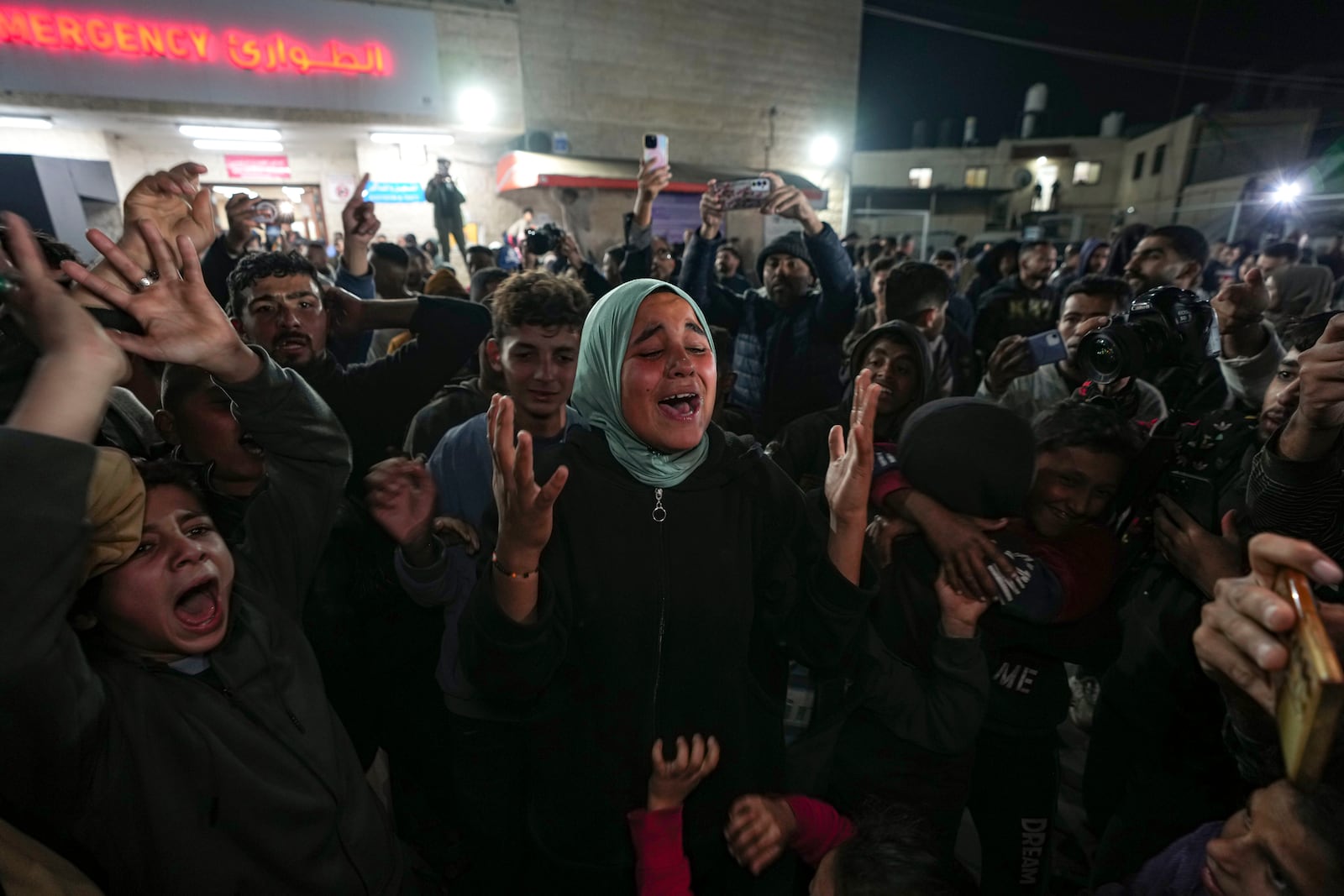 Palestinians celebrate the announcement of a ceasefire deal between Hamas and Israel in Deir al-Balah, central Gaza Strip, Wednesday, Jan. 15, 2025. (AP Photo/Abdel Kareem Hana)