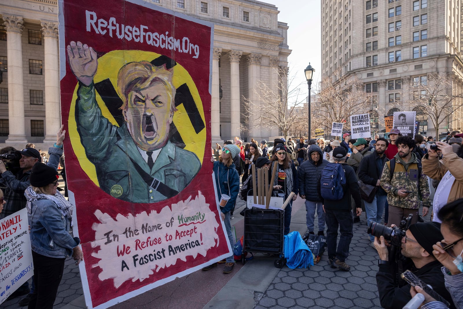 Demonstrators raise a sign depicting President Donald Trump as Adolf Hitler during a protest in support of Palestinian activist Mahmoud Khalil, Monday, March 10, 2025, in New York. (AP Photo/Yuki Iwamura)