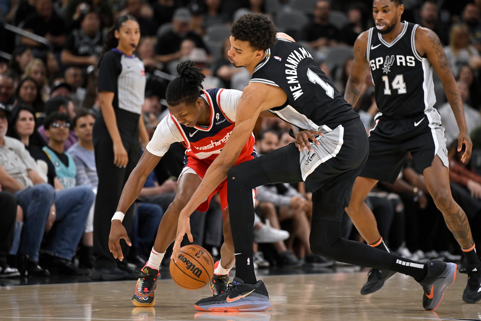 San Antonio Spurs forward Victor Wembanyama (1) and Washington Wizards guard Bub Carrington fight for possession during the second half of an NBA basketball game, Wednesday, Nov. 13, 2024, in San Antonio. San Antonio won 139-130. (AP Photo/Darren Abate)