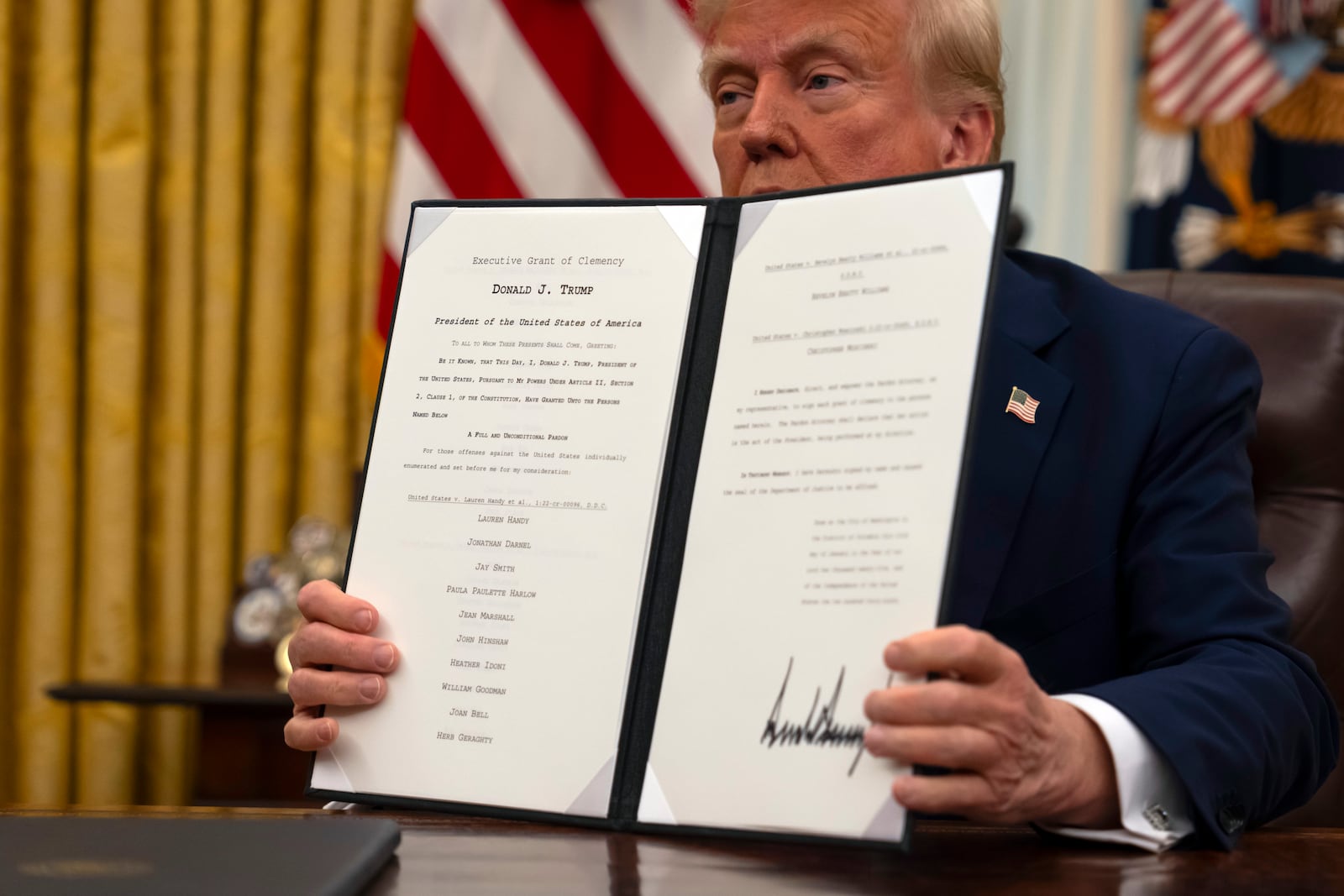 President Donald Trump holds up a signed executive order relating to clemency for anti-abortion protesters as he signs executive orders in the Oval Office of the White House, Thursday, Jan. 23, 2025, in Washington. (AP Photo/Ben Curtis)