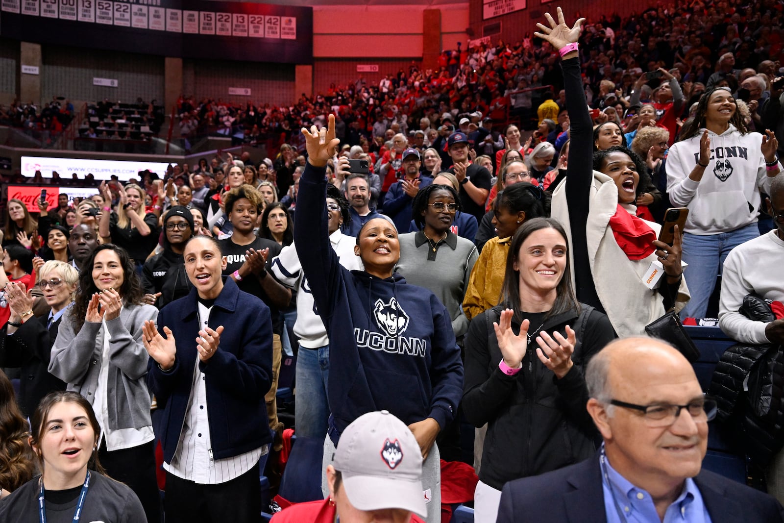 Former players including Sue Bird, Diana Taurasi, Maya Moore and Kelly Faris, front row from left, cheer for their former coach during a pregame ceremony honoring Geno Auriemma and longtime assistant Chris Dailey, Wednesday, Nov. 20, 2024, in Storrs, Conn. (AP Photo/Jessica Hill)