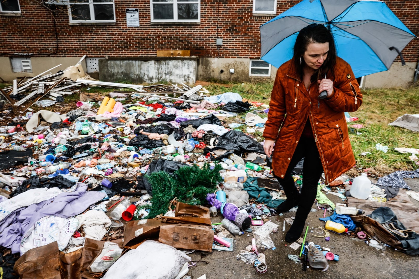 Lynn Lamance walks through trash dumped behind an apartment on Santa Clara Ave. in Dayton. The building appears to have some construction activity but has become a neighborhood dumping ground. JIM NOELKER/STAFF